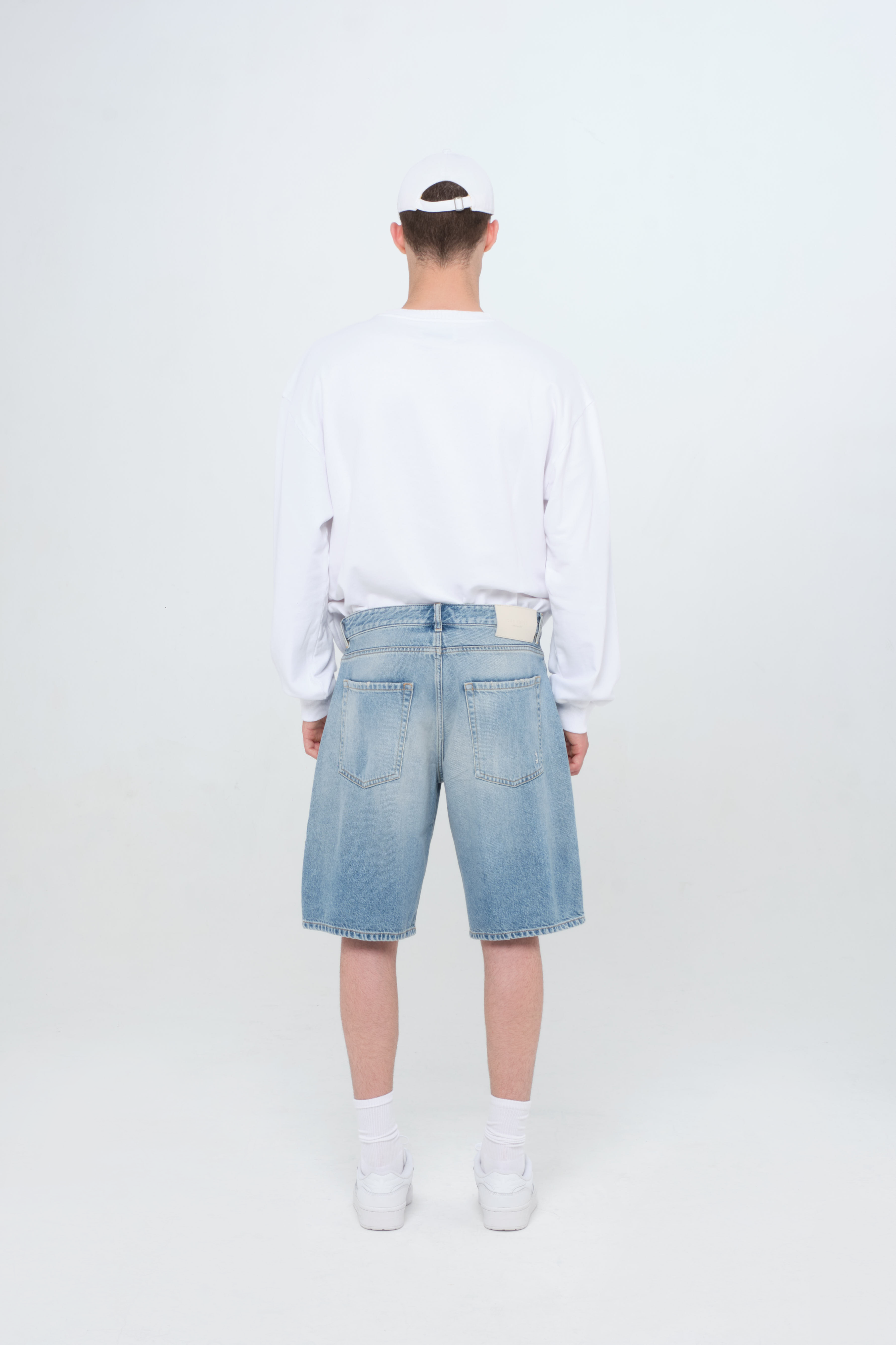 Back view of Bobby men’s short jeans in smoke blue wash, 100% rigid cotton denim, worn by a model with a white sweatshirt.