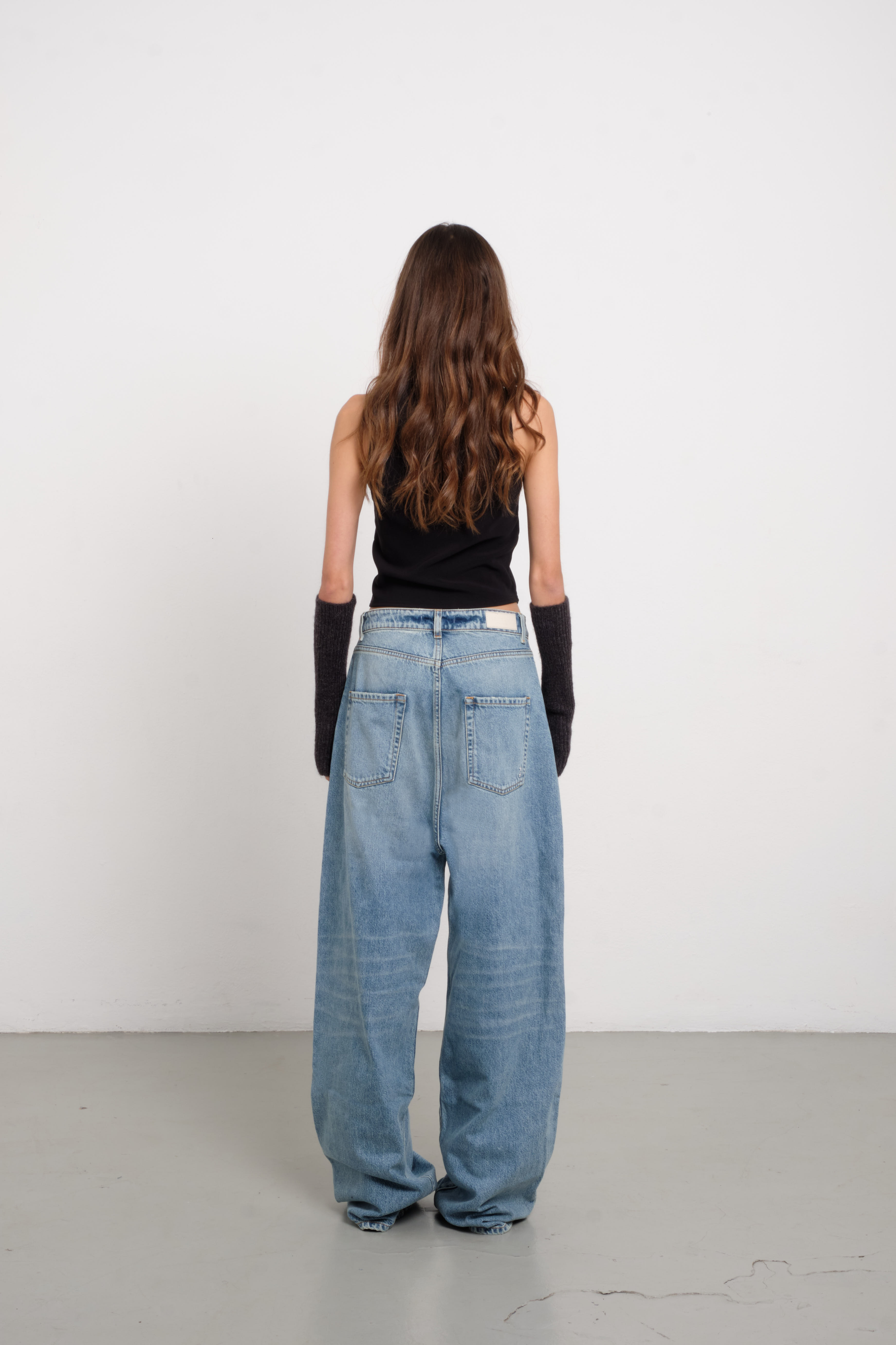 Back view of Coco women’s wide leg jeans in light wash, 100% rigid cotton denim, worn by a model with a black top.