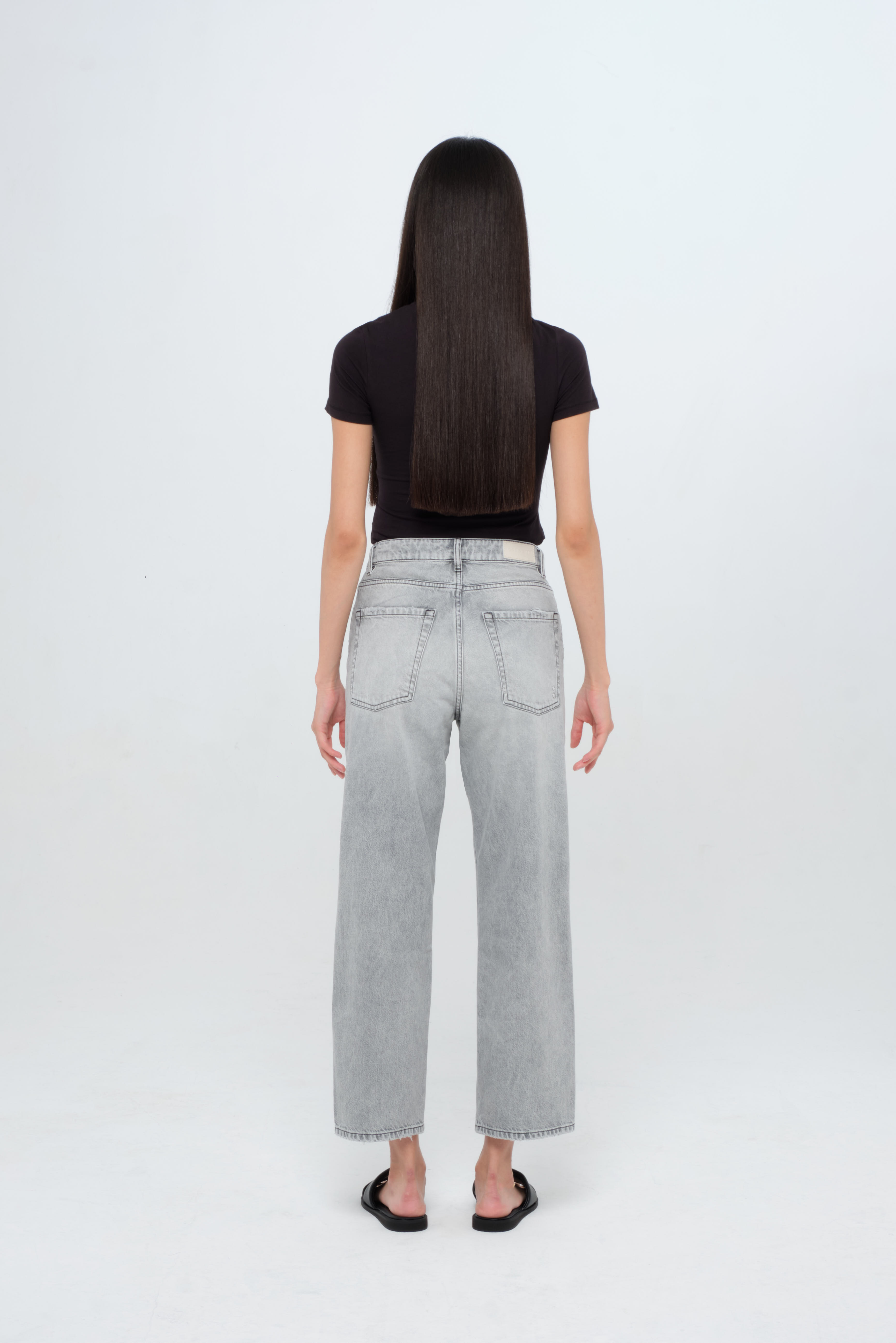 Back view of Jill women’s straight leg jeans in gray wash, 100% rigid cotton denim, worn by a model with a black top.