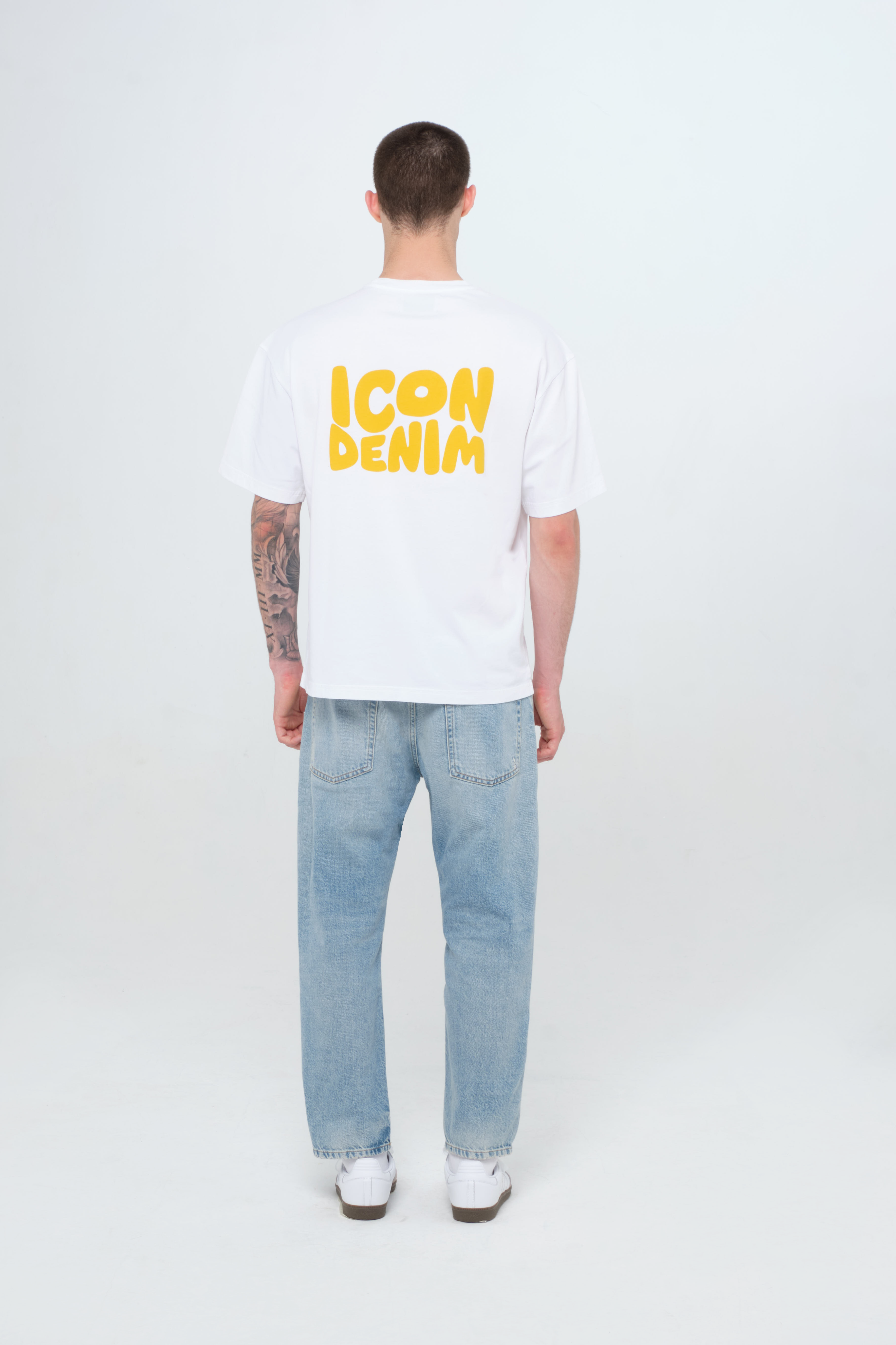 Back view of Josh men’s carrot jeans in light wash, 100% rigid cotton denim, worn by a model with a white t-shirt.