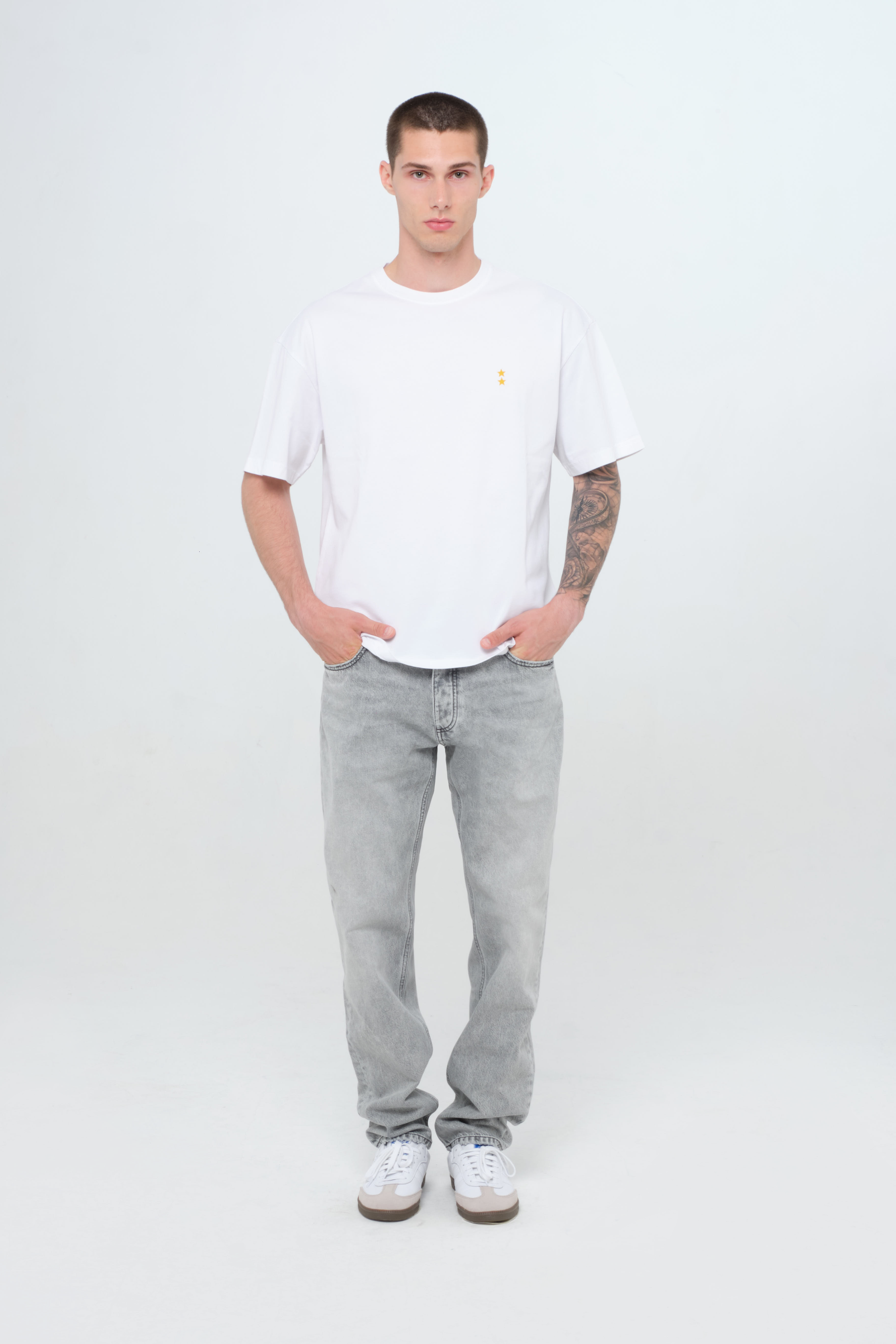Kanye men’s loose jeans in gray wash, 100% rigid cotton denim, worn by a model with a white t-shirt.
