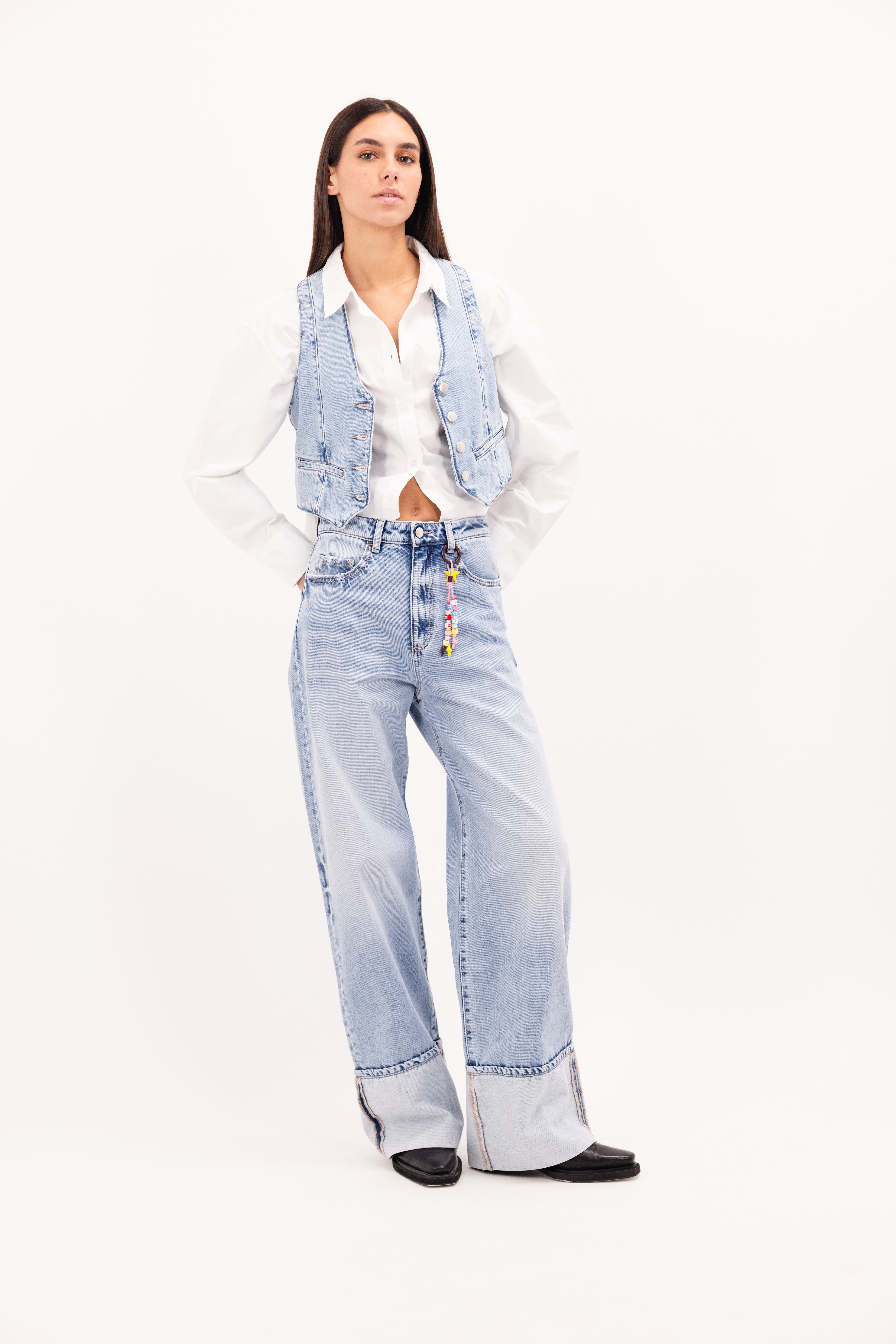 Kiki women’s wide leg jeans in sky blue wash, 100% rigid cotton denim, worn by a model with a shirt and denim vest.