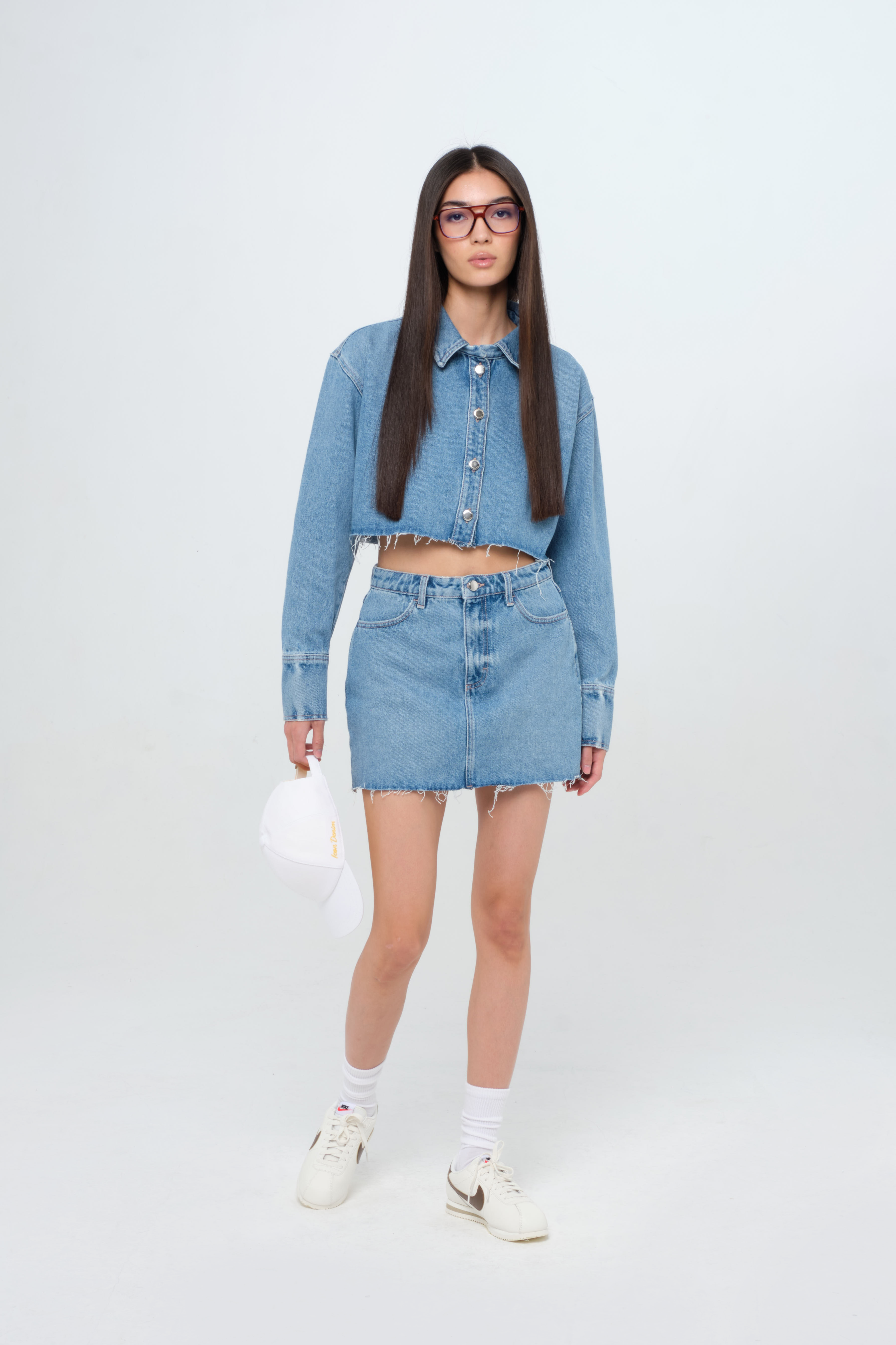 Nelly Eco women’s short skirt in medium wash, 100% rigid organic cotton denim, worn by a model with a crop denim shirt.