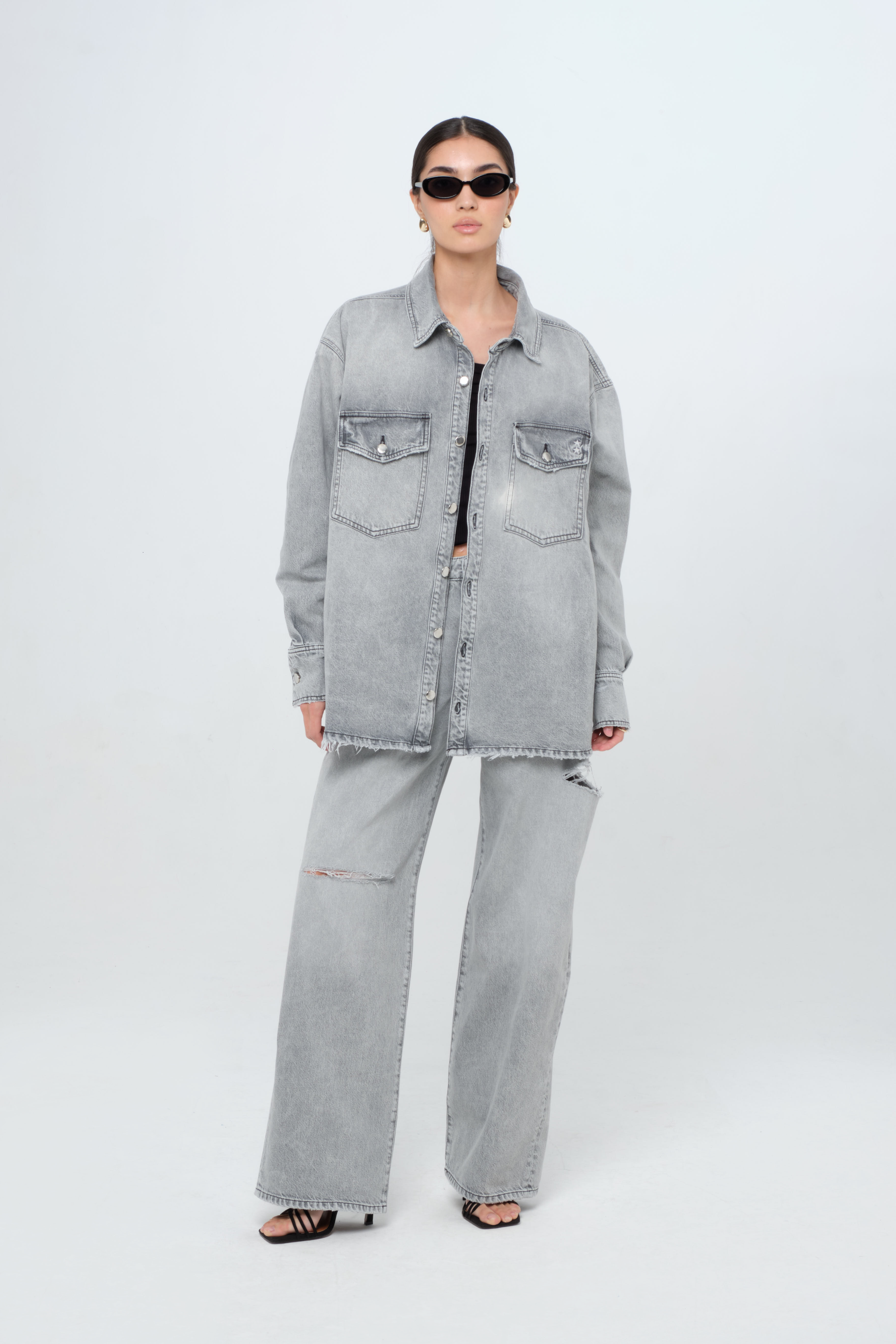 Noa women’s oversize shirt in gray wash, 100% rigid cotton denim, worn by a model with jeans.