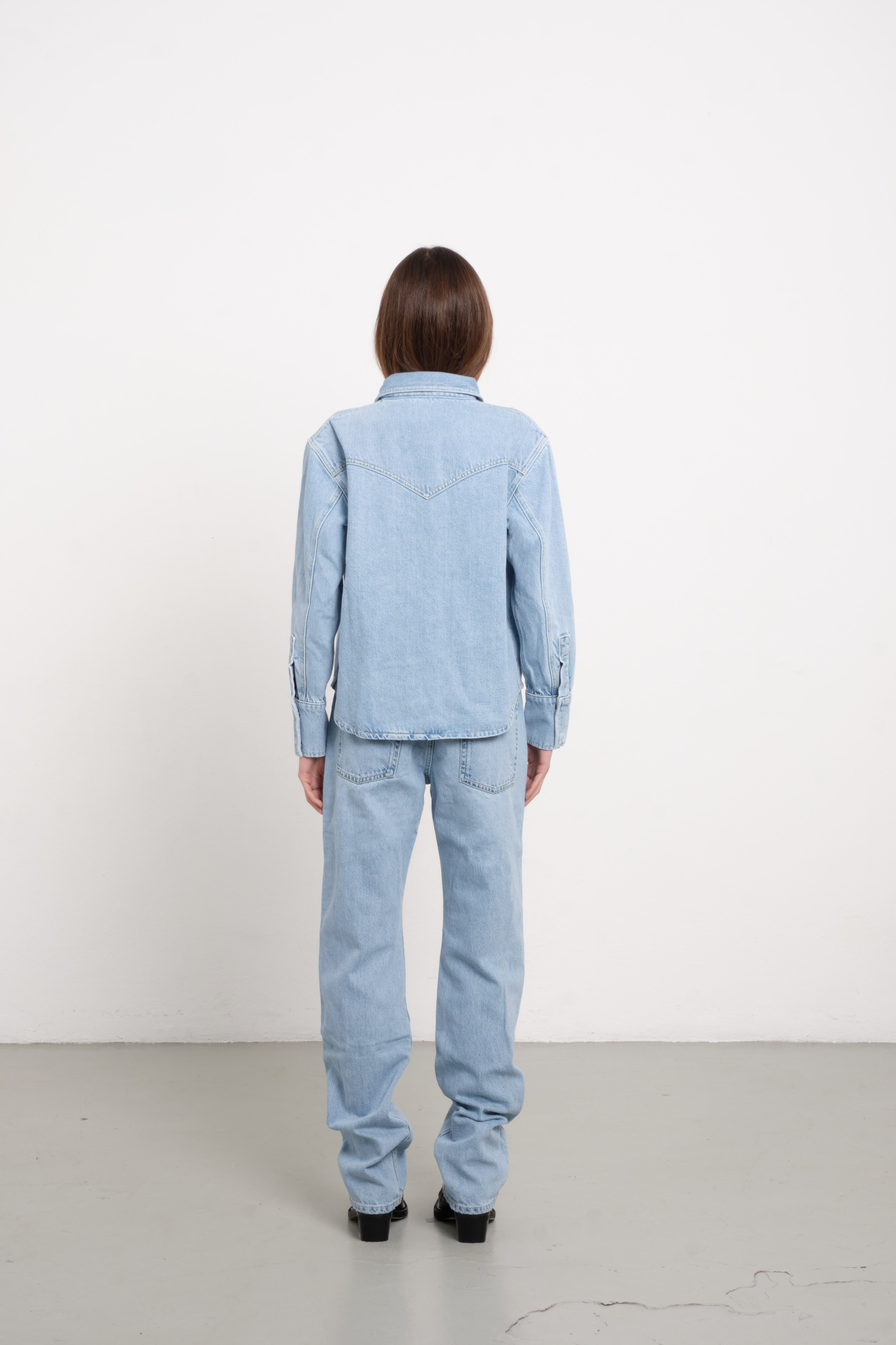Back view of Norah women’s regular shirt in light wash, 100% rigid cotton denim, worn by a model with jeans.