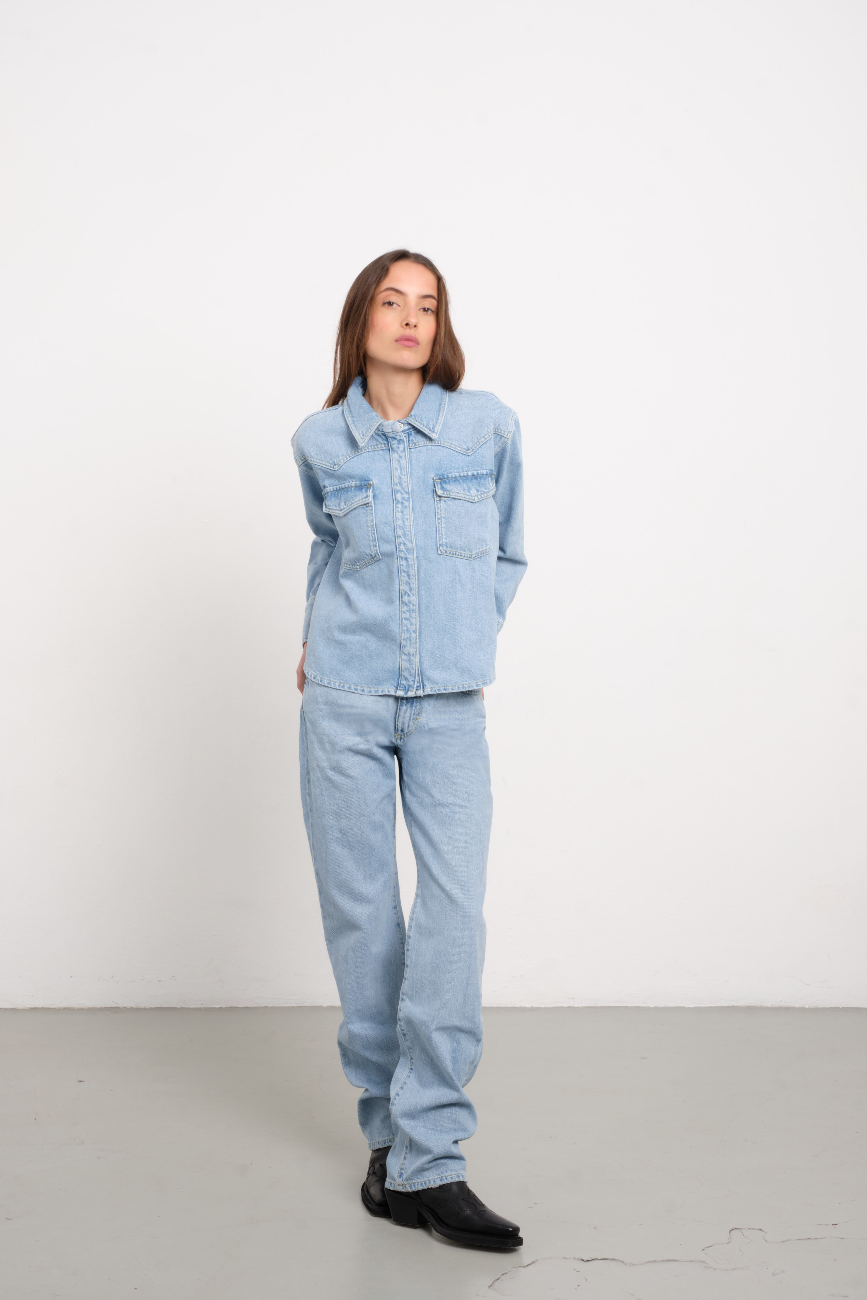 Norah women’s regular shirt in light wash, 100% rigid cotton denim, worn by a model with jeans.