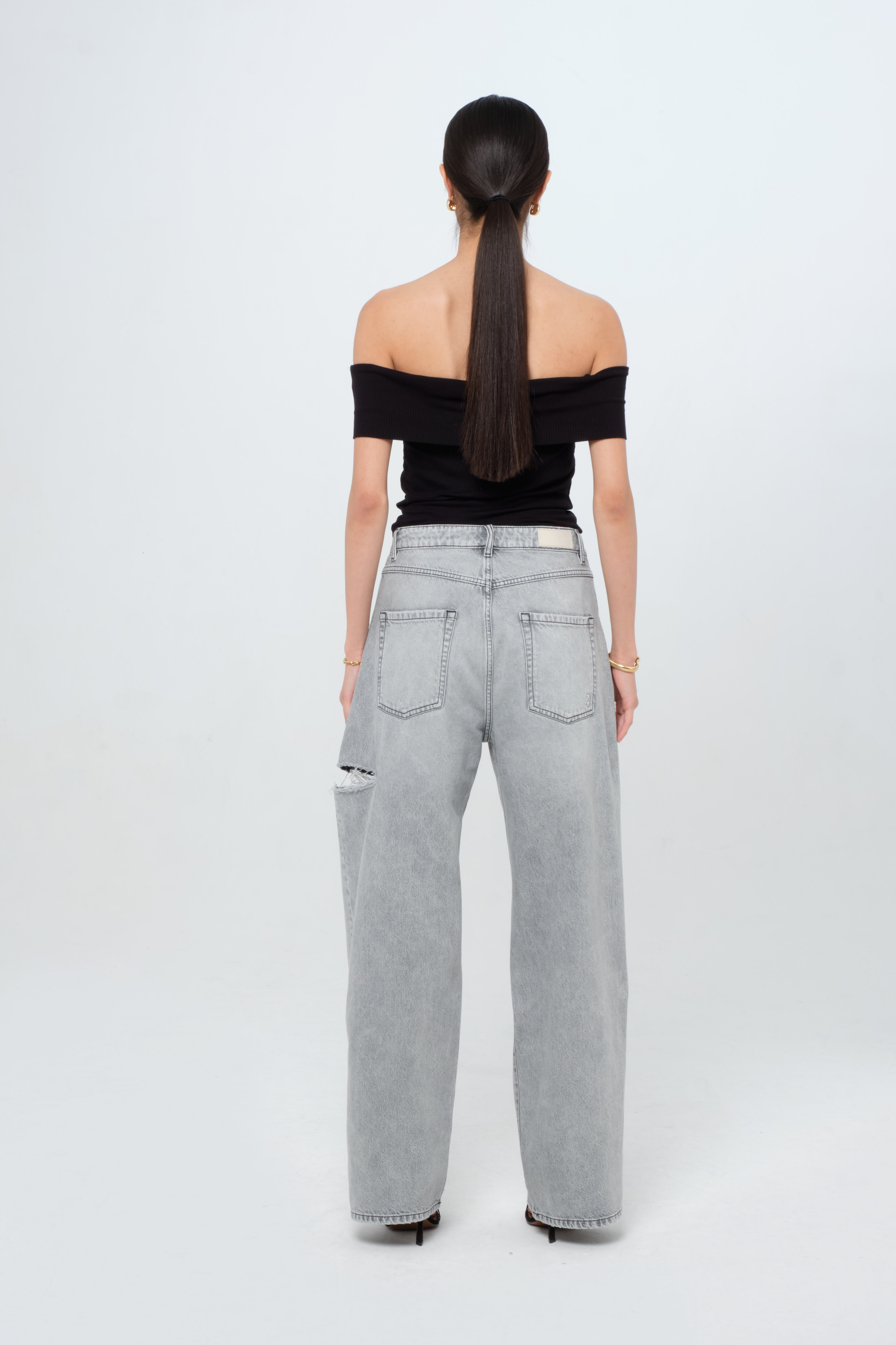 Back view of Poppy women’s wide leg jeans in gray wash, 100% rigid cotton denim, worn by a model with a black top.