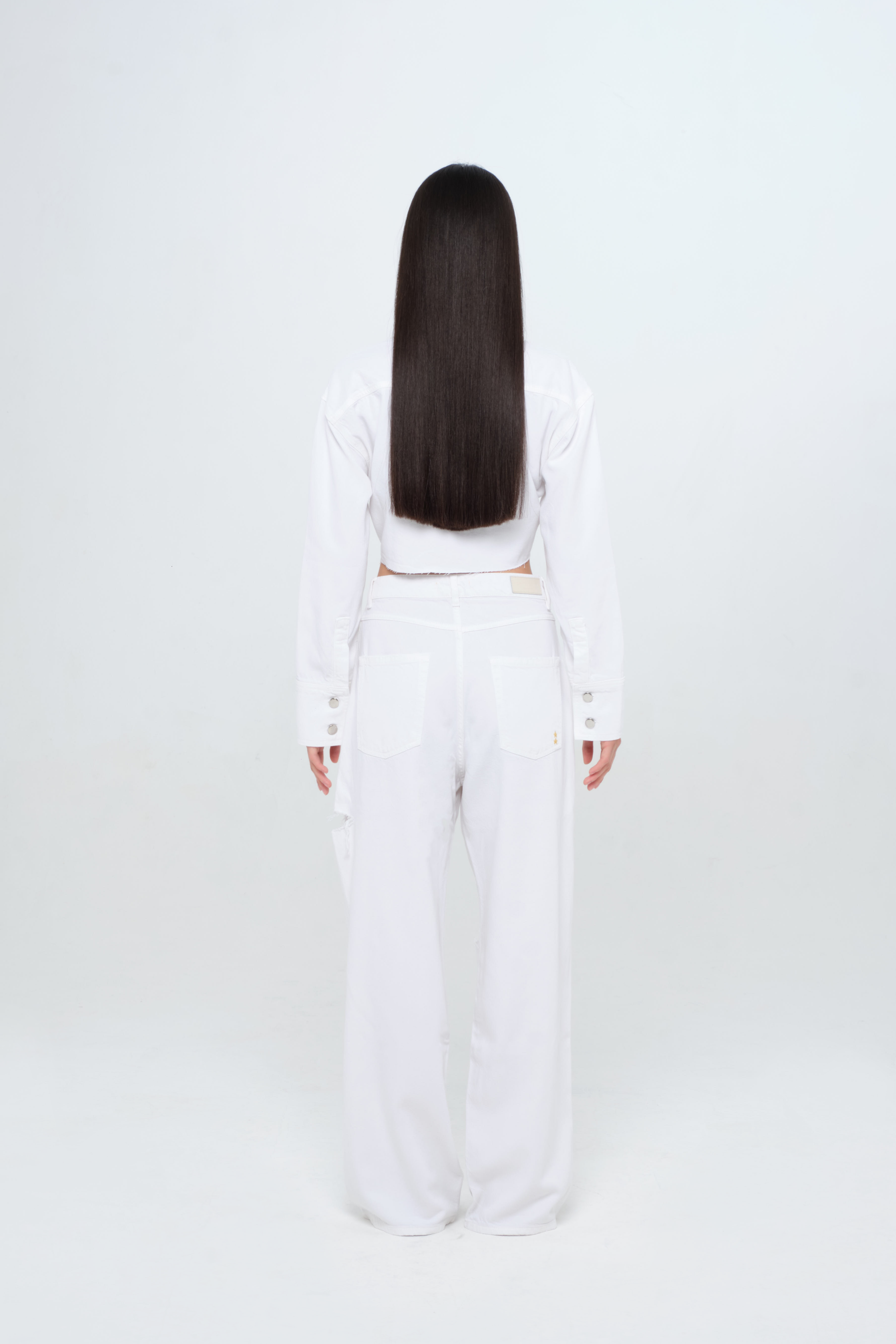 Back view of Poppy women’s wide leg jeans in white, 100% rigid soft cotton denim, worn by a model with a white denim shirt.