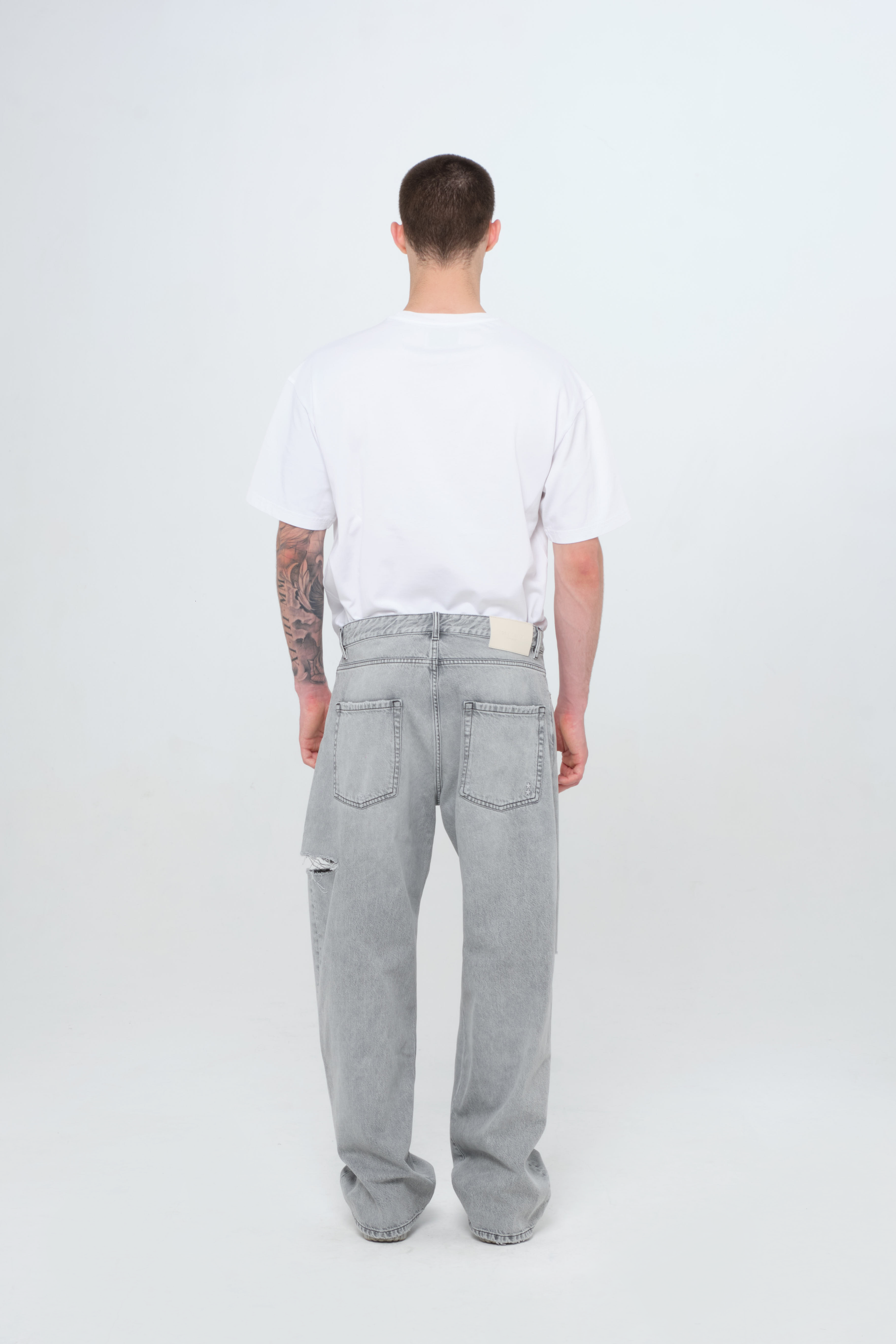 Back view of Scott men’s wide leg jeans in gray wash, 100% rigid cotton denim, worn by a model with a white t-shirt.