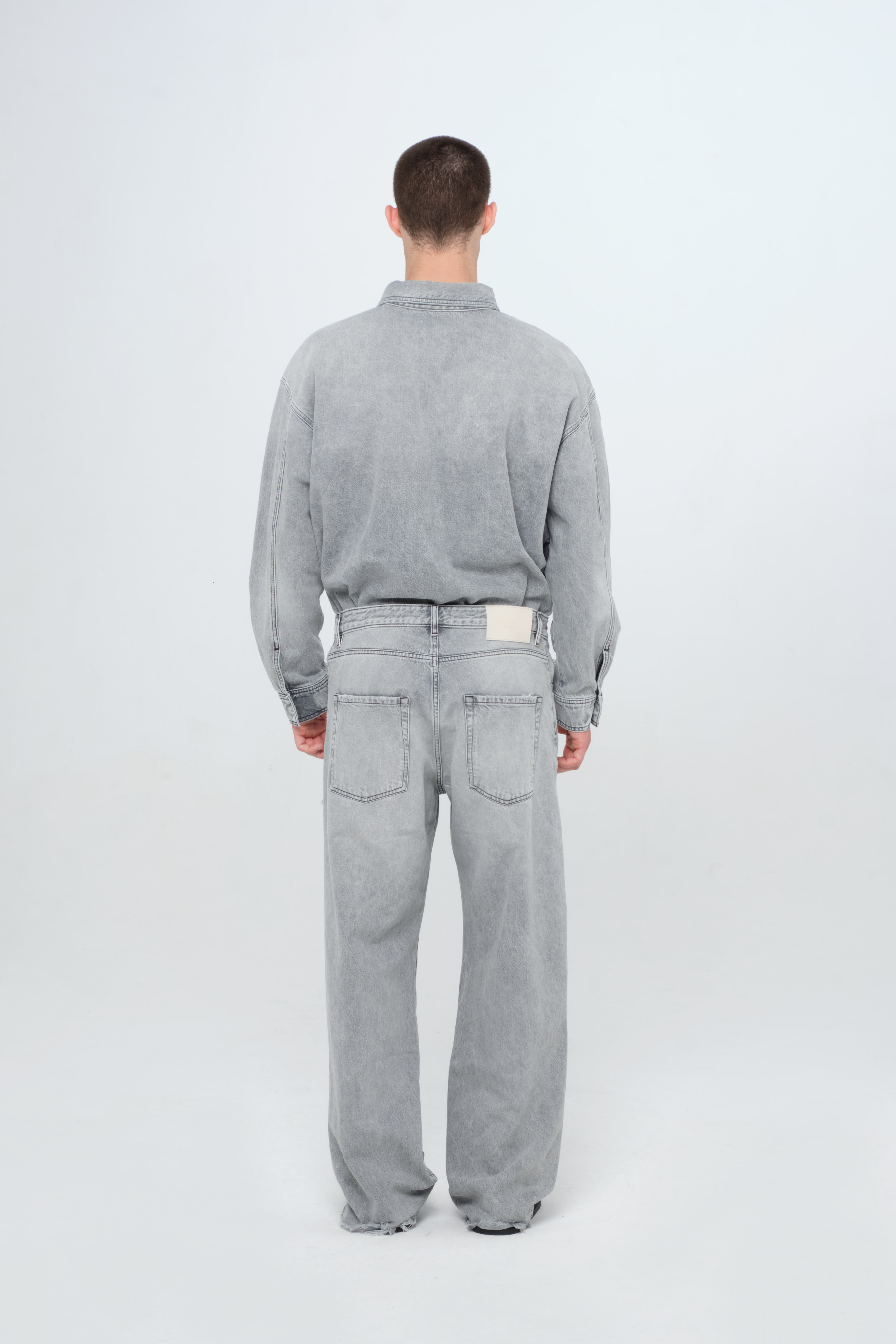Back view of Will men’s wide leg jeans in gray wash, 100% rigid cotton denim, worn by a model with a denim shirt.