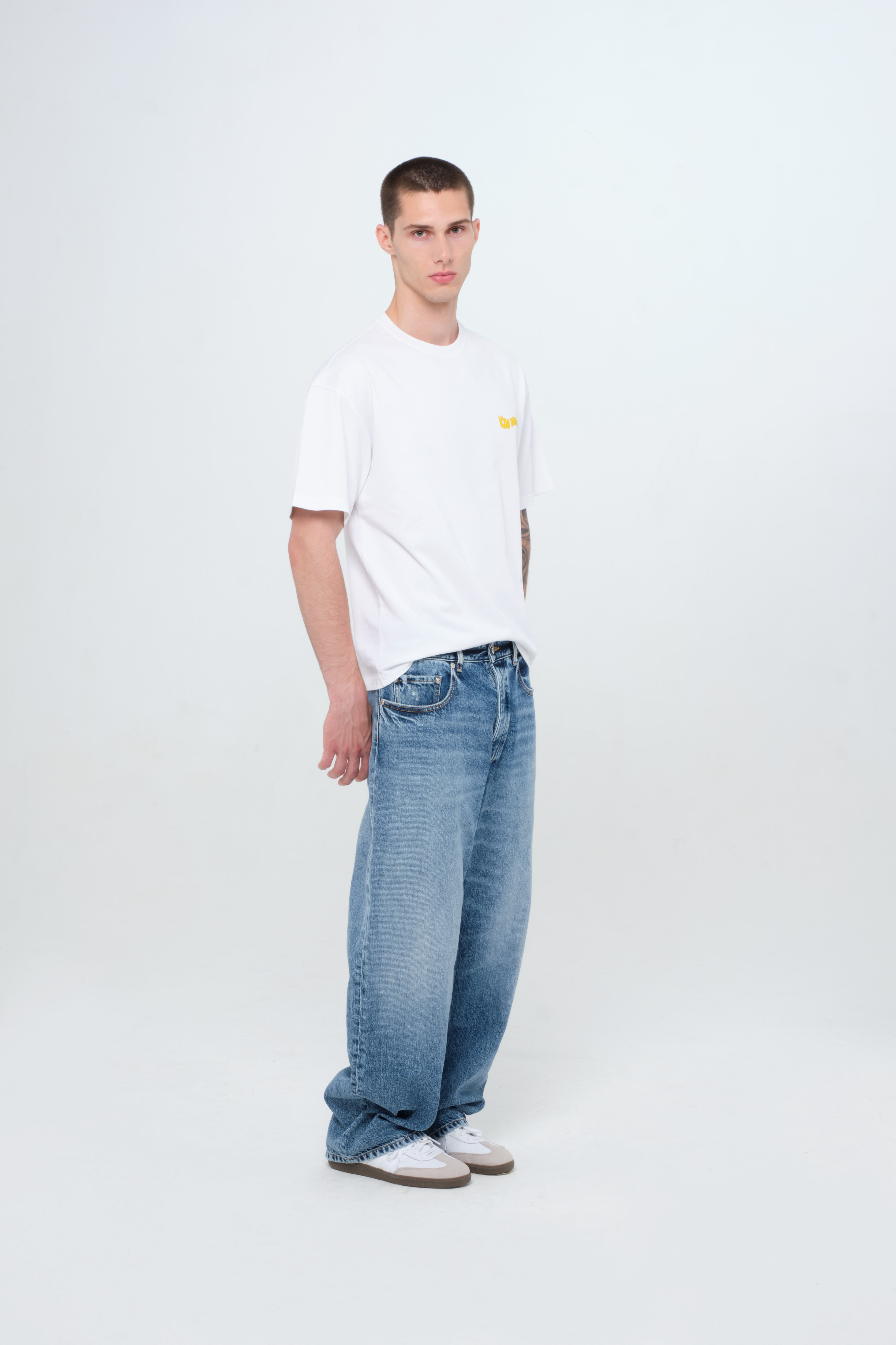 Back view of Will men’s wide leg jeans in medium wash, 100% rigid cotton denim, worn by a model with a white t-shirt.
