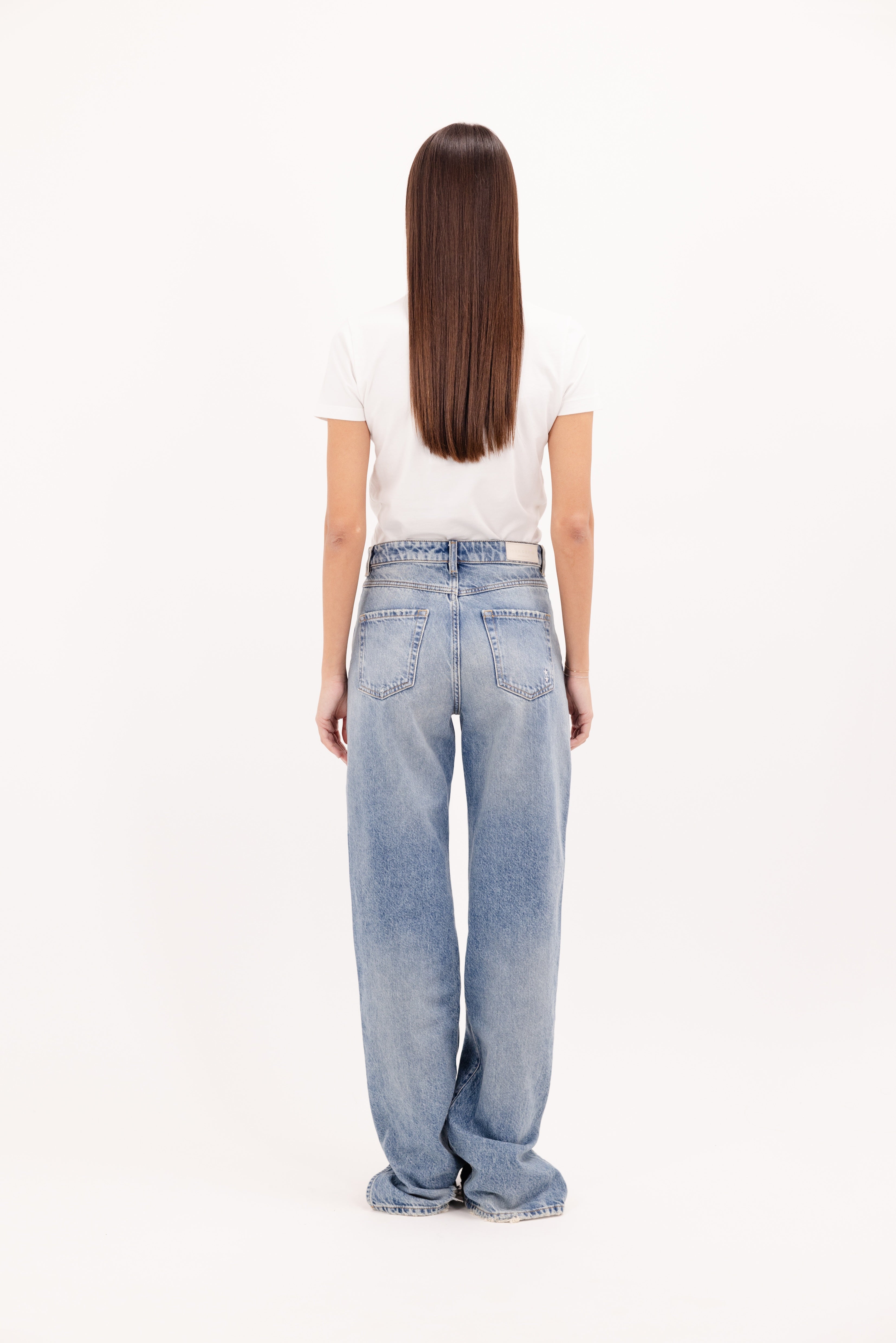 Back view of Jodie women’s straight leg jeans in smoke blue wash, 100% rigid cotton denim, worn by a model with a white t-shirt.