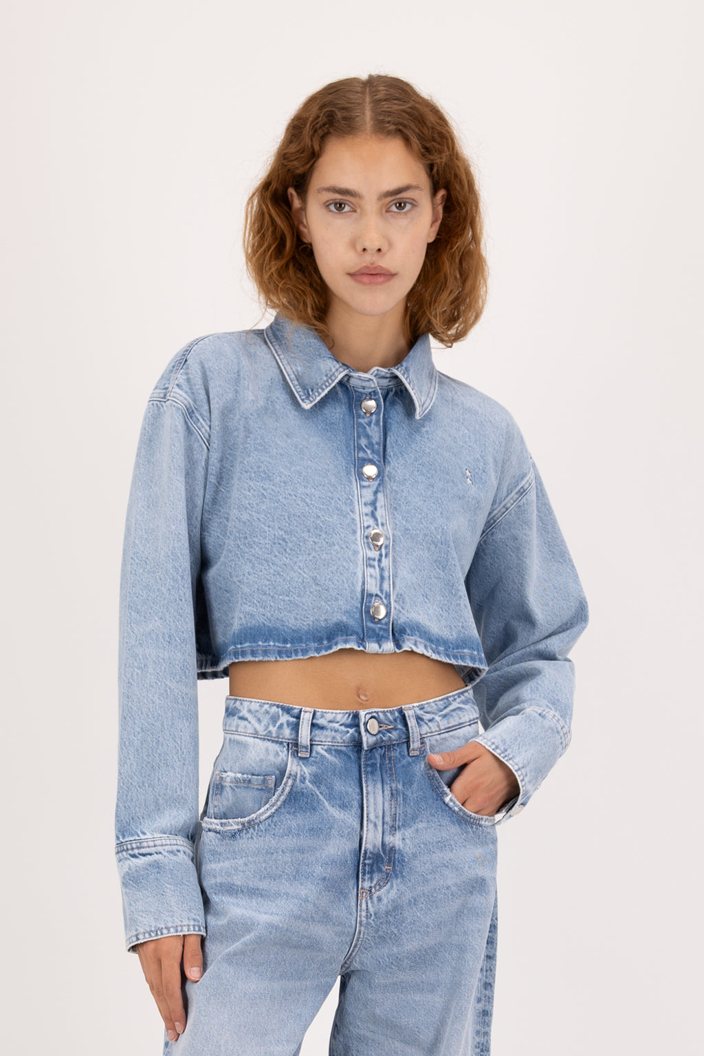 Amber Eco women’s cropped shirt in arid blue wash, 100% organic rigid cotton denim, worn by a model with jeans.