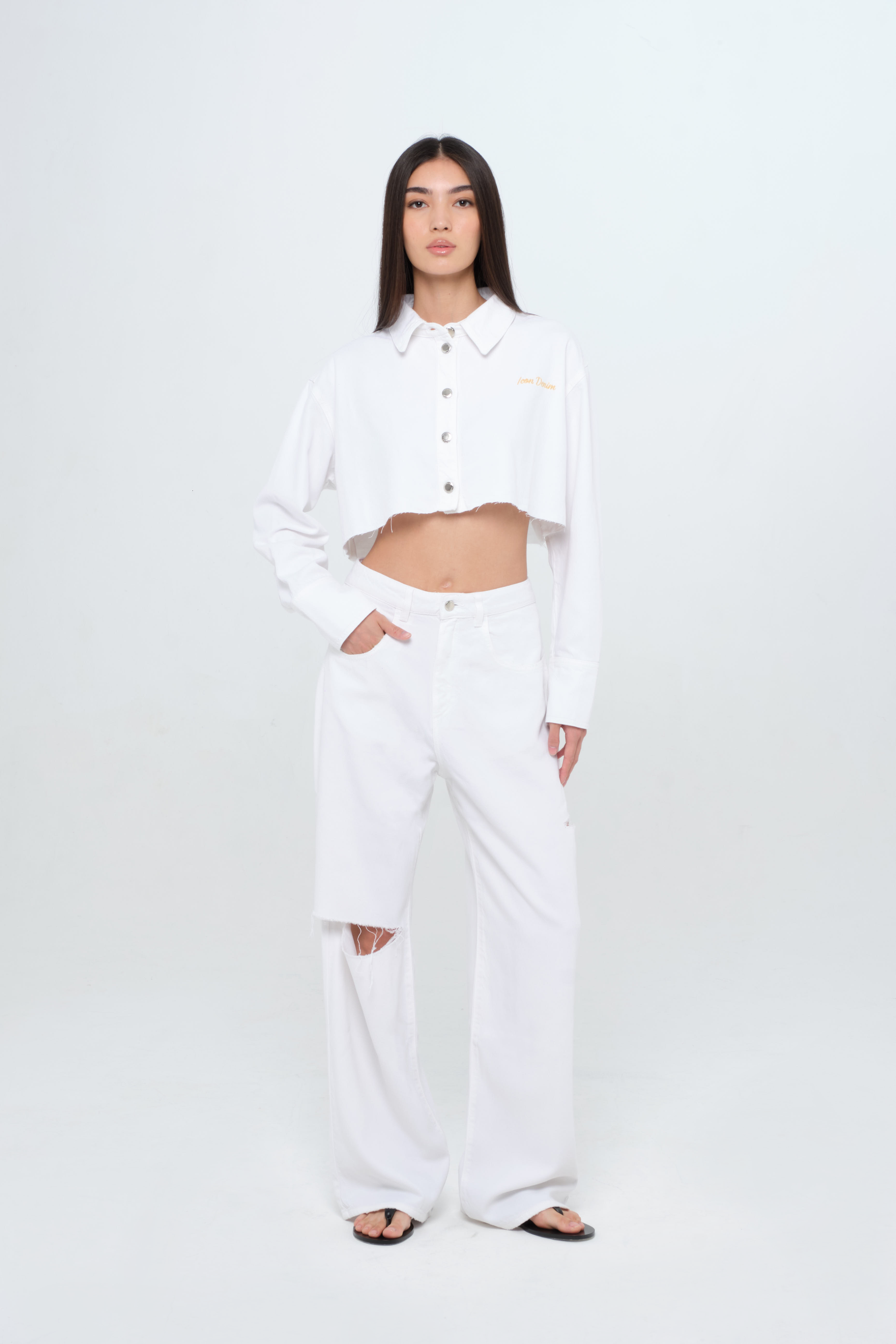 Amber women’s denmi crop shirt in white, 100% rigid soft cotton denim, worn by a model with a white jeans.
