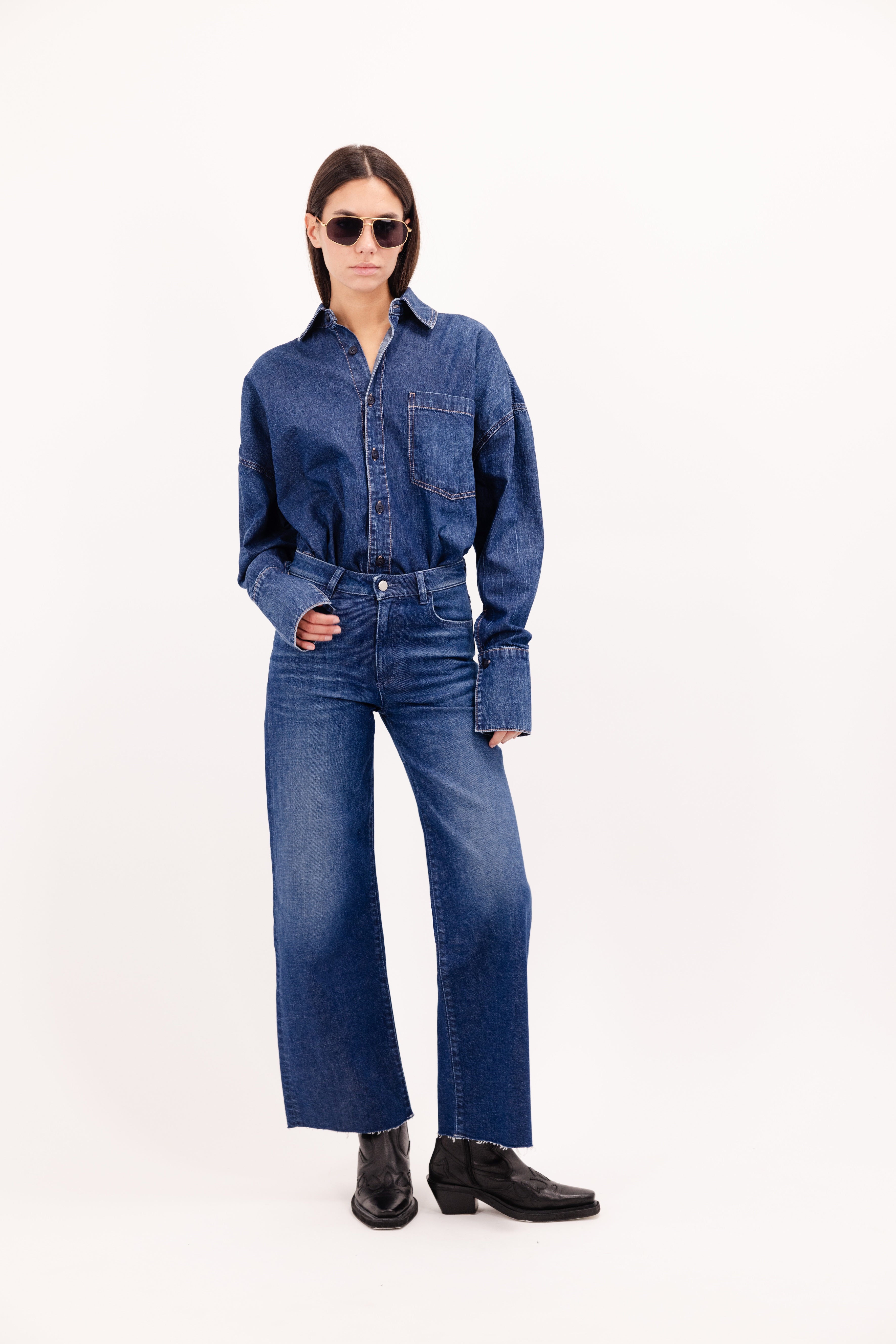 Angie women’s flared crop jeans in dusty blue wash, 99% cotton denim and 1% Elastan fibers, worn by a model with a denim shirt.