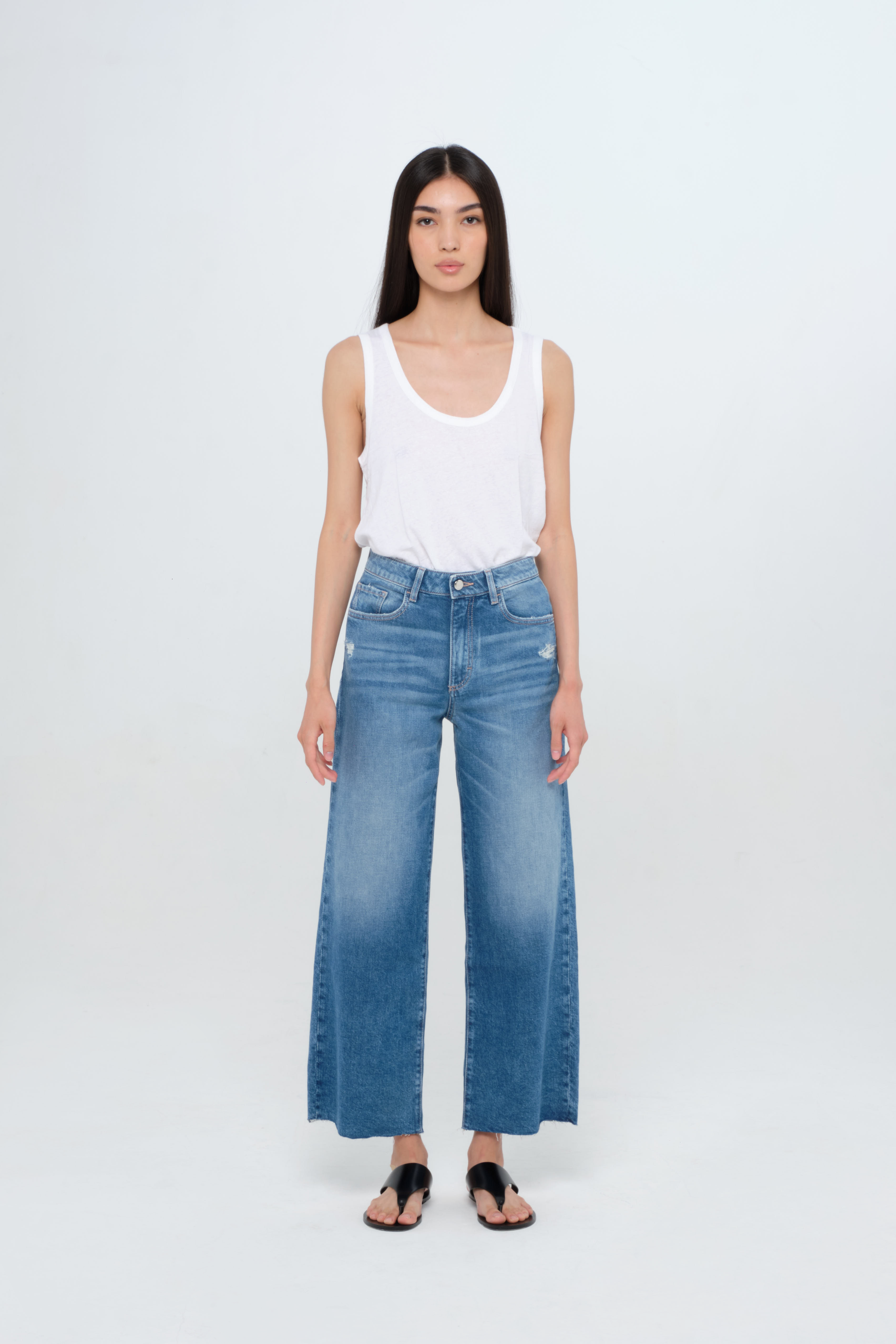 Angie women’s flared crop jeans in medium wash, 100% cotton denim, worn by a model with a white tank top