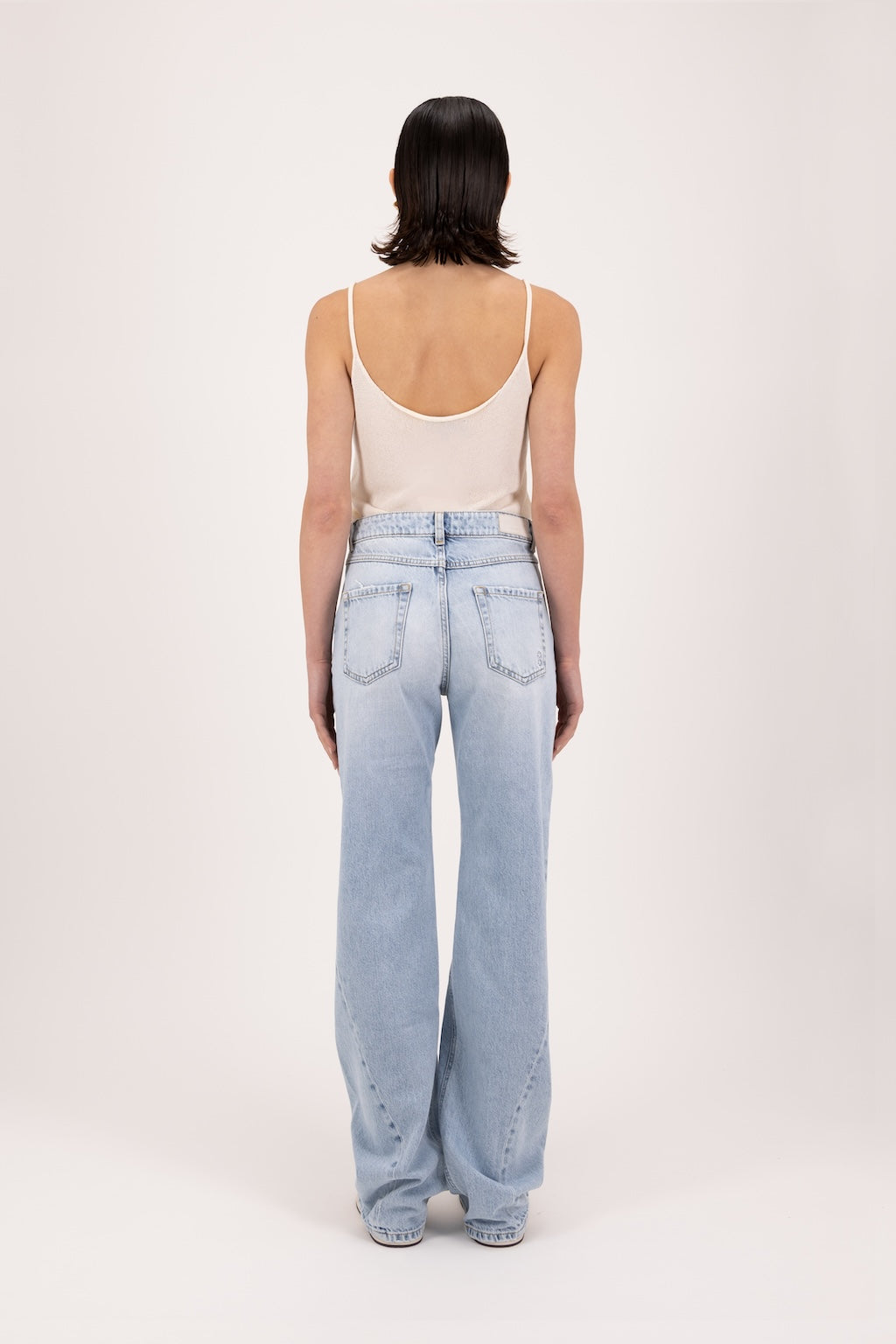 Back view of Annie women’s straight leg jeans in sky blue wash, 100% rigid cotton denim, worn by a model with a white tank top.