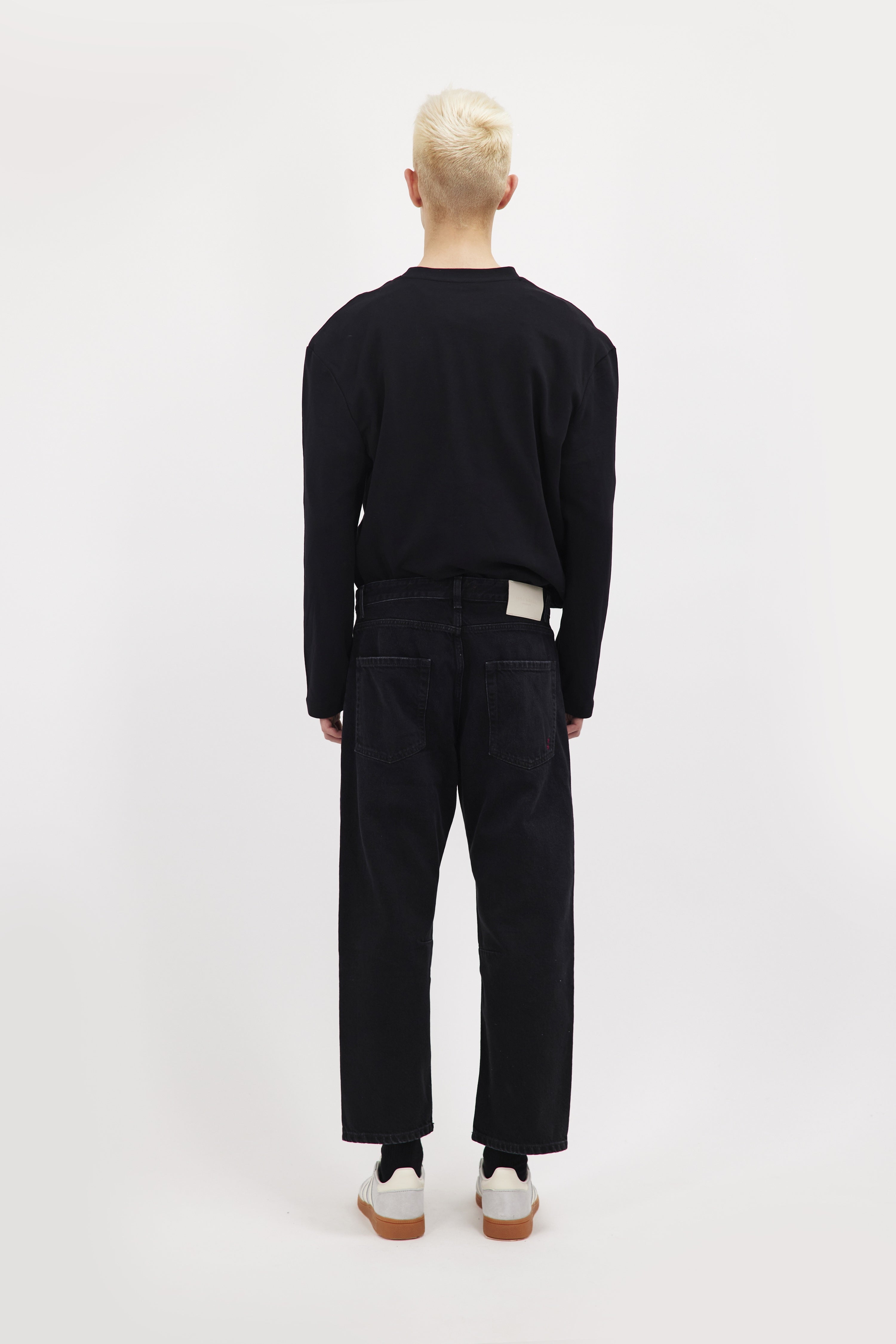 Back view of Ash men's baggy-cut jeans in graphite black wash, 100% rigid cotton denim, worn by a model with a black sweatshirt.