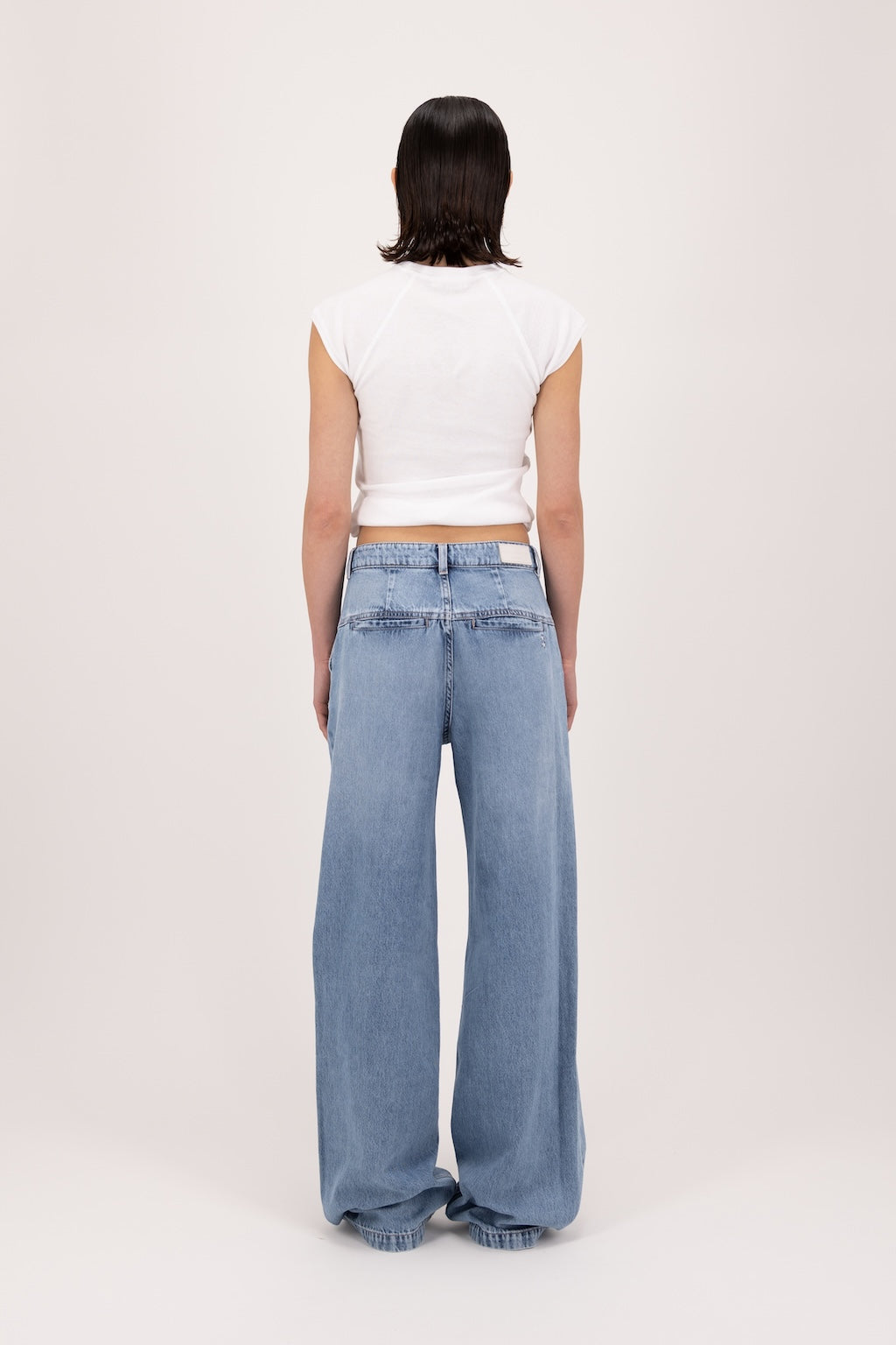 Back view of Ava women’s wide leg jeans in river wash, 100% rigid soft cotton denim, worn by a model with a white top.