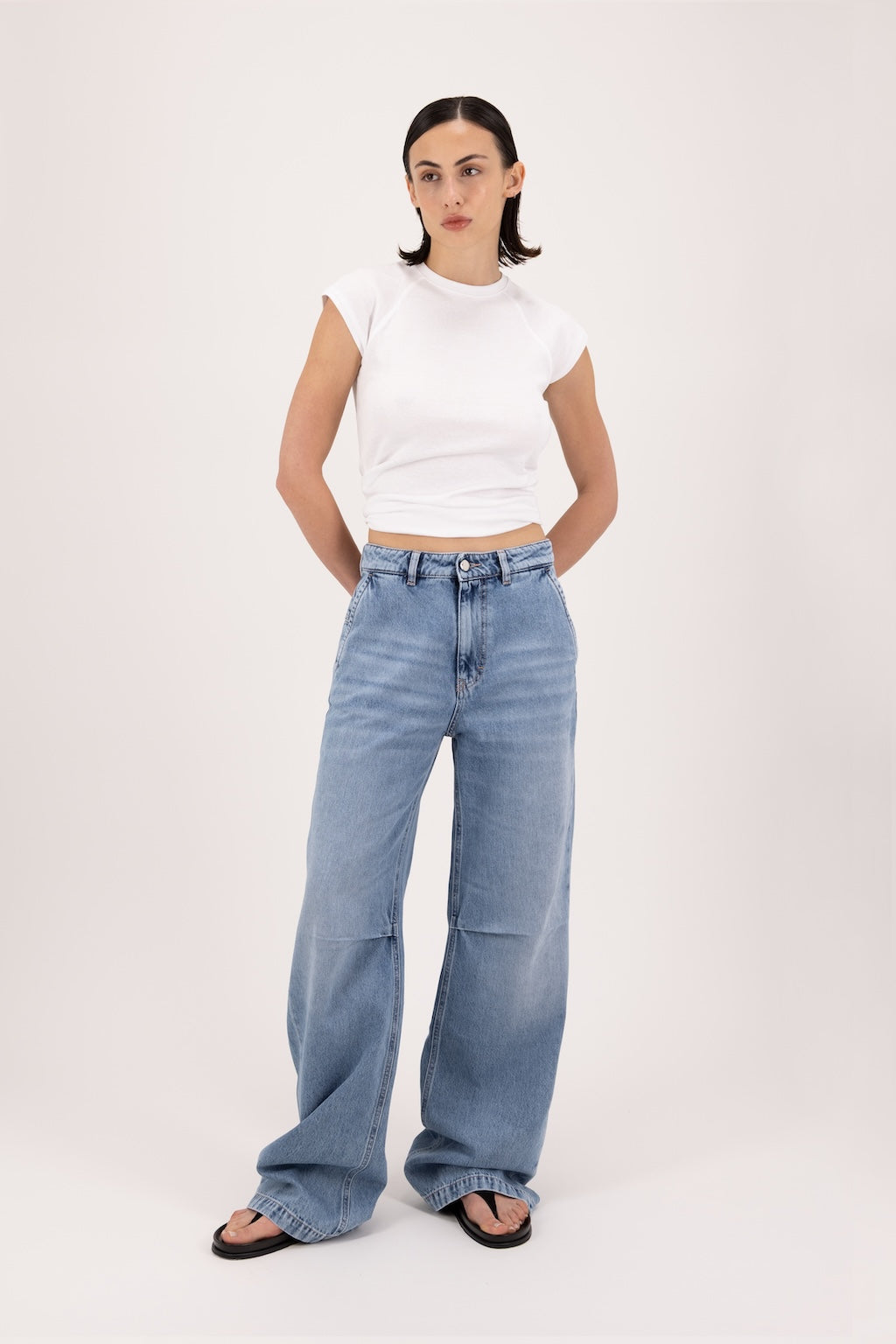 Ava women’s wide leg jeans in river wash, 100% rigid soft cotton denim, worn by a model with a white top.