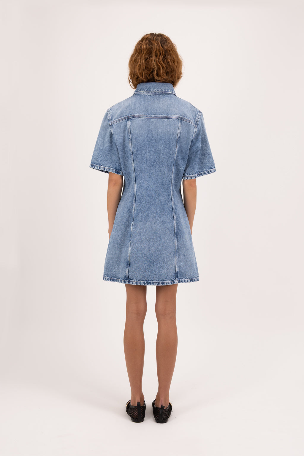 Back view of Bambi women’s dress in river wash, 100% rigid cotton denim, worn by a model.
