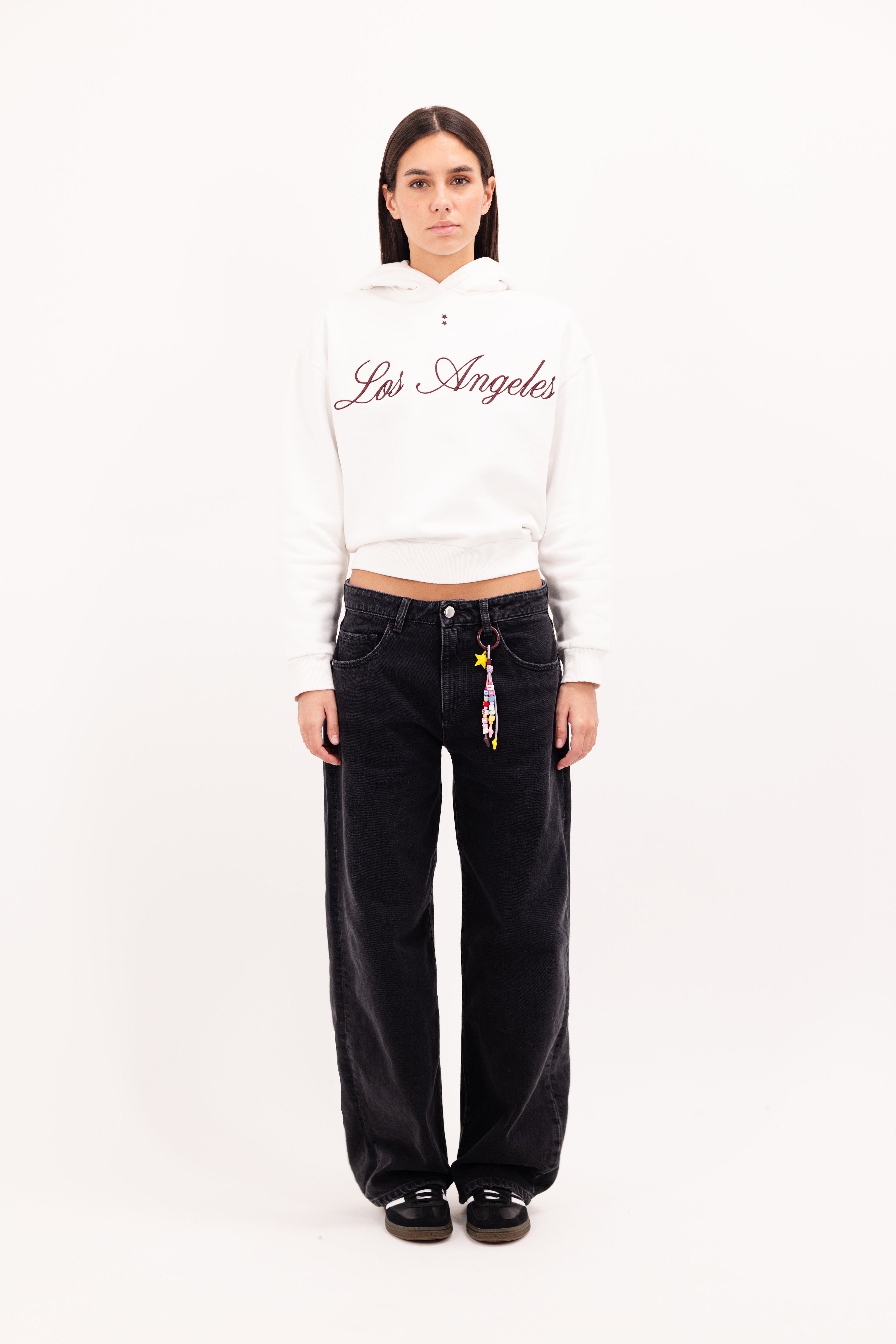 Bea women’s wide leg jeans in graphite black wash, 100% rigid cotton denim, worn by a model with a white hoodie.