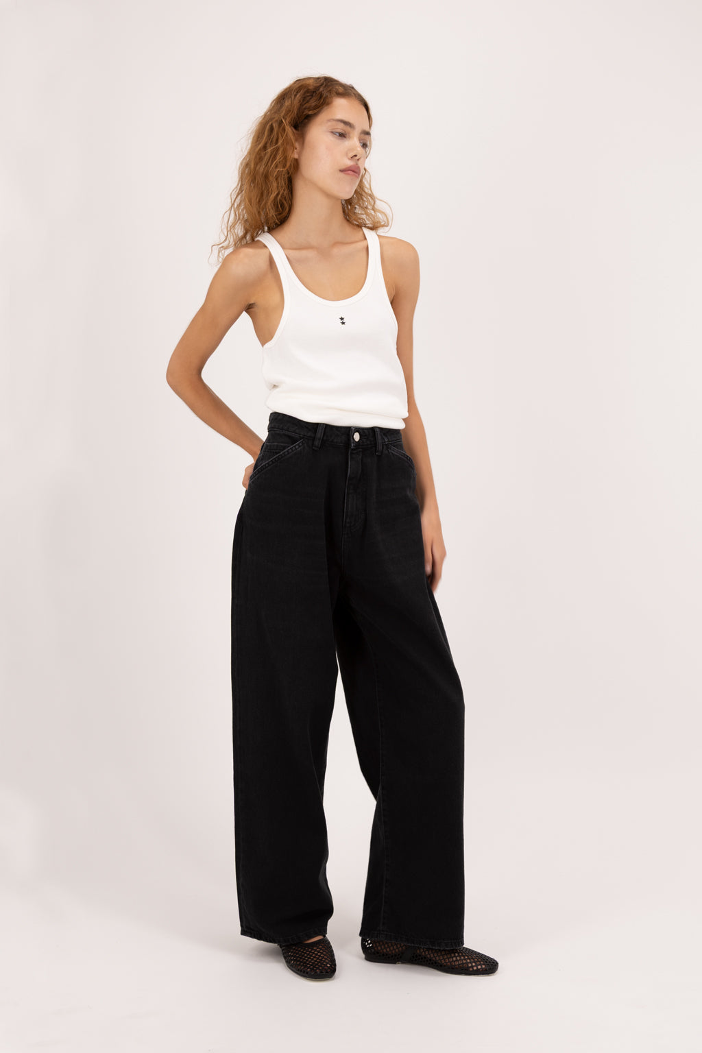 Bess women’s wide leg jeans in graphite black wash, 100% rigid soft cotton denim, worn by a model with a white tank top.