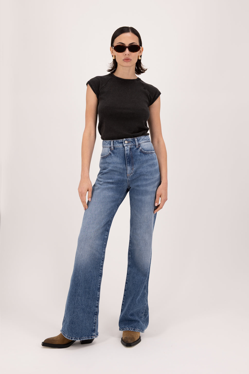 Blue women’s flared leg jeans in eclipse wash, 100% rigid cotton denim, worn by a model with a black t-shirt.