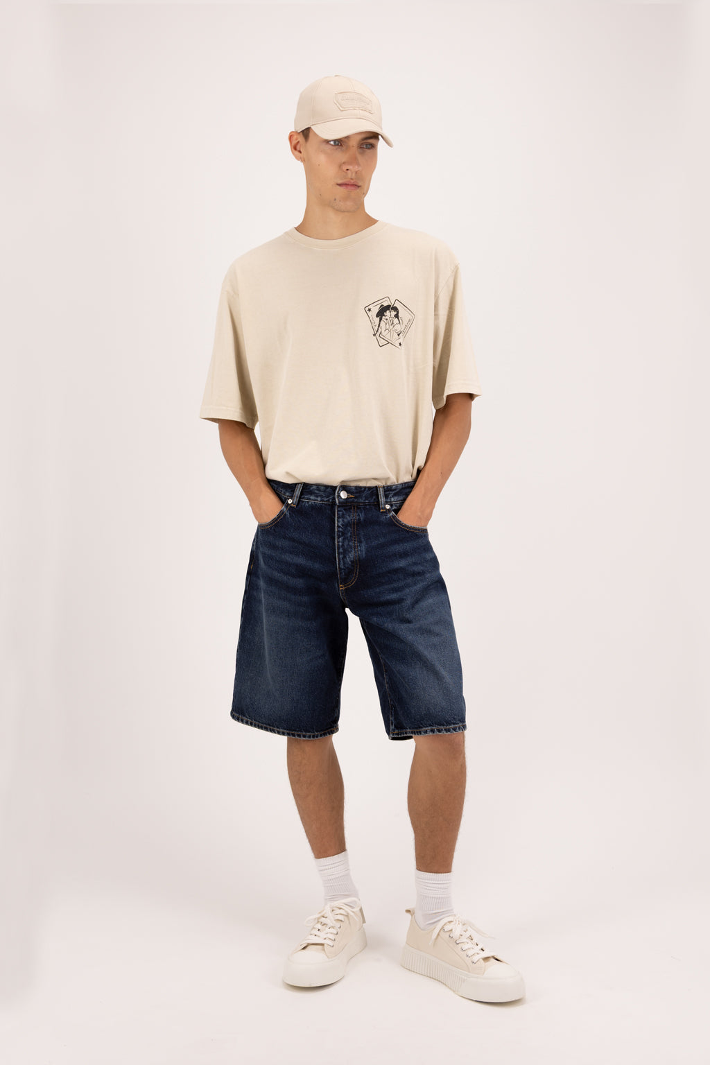 Bobby men’s short jeans in deep blue wash, 100% rigid cotton denim, worn by a model with a desert t-shirt.
