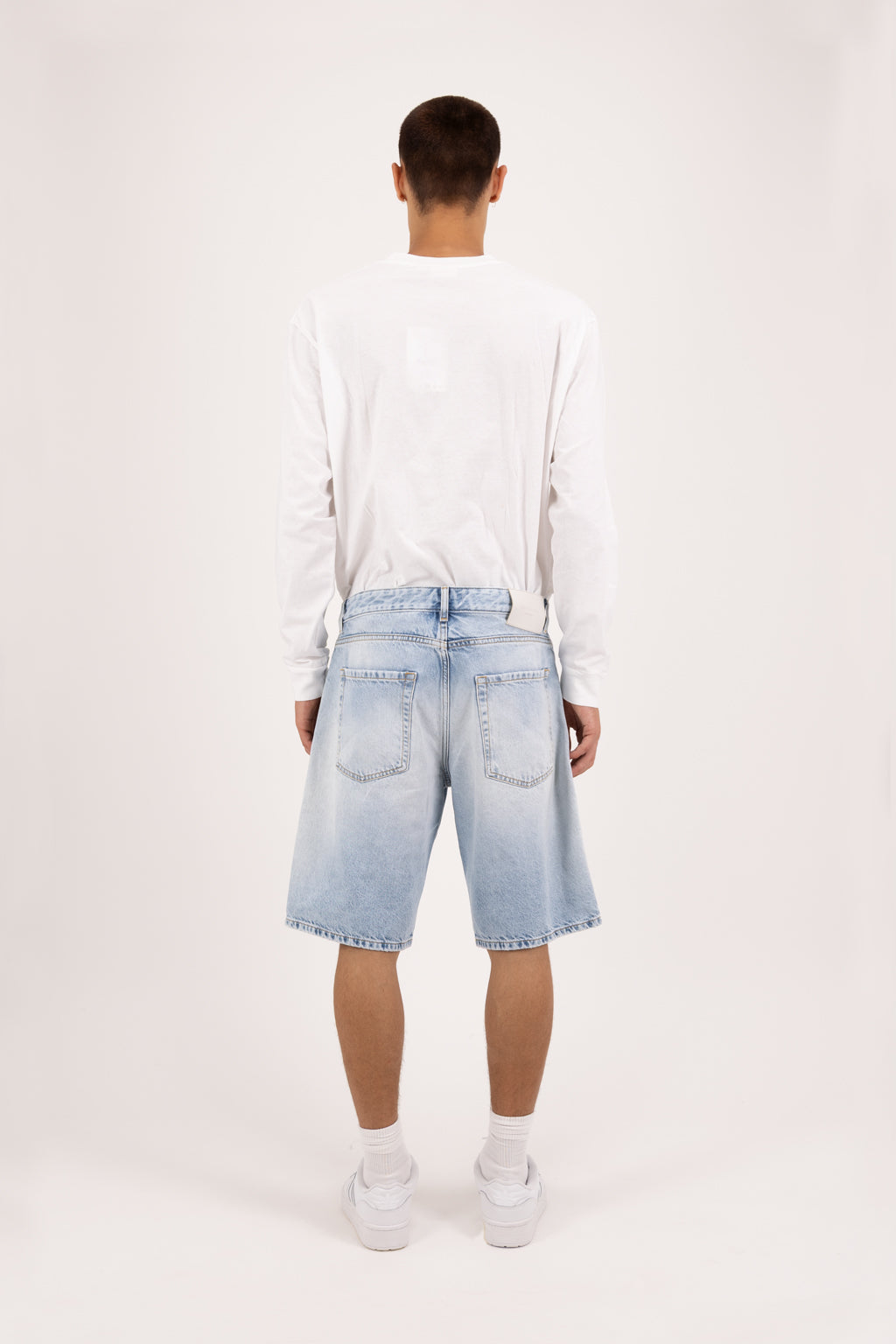 Back view of Bobby men’s short jeans in sky blue wash, 100% rigid cotton denim, worn by a model with a white longsleeve.