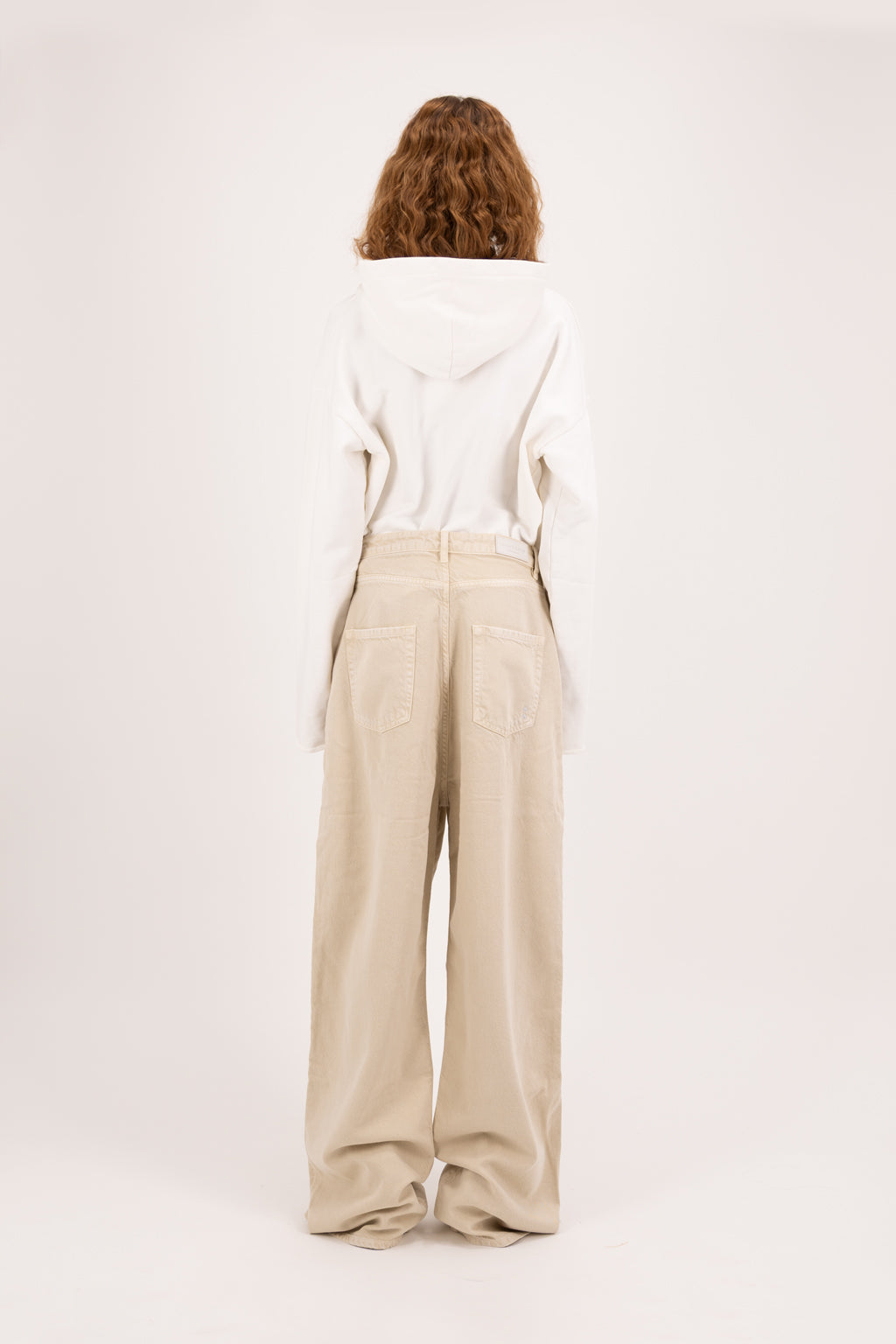 Back view of Coco women’s wide leg jeans in desert wash, 100% rigid soft cotton denim, worn by a model with a denim jacket.