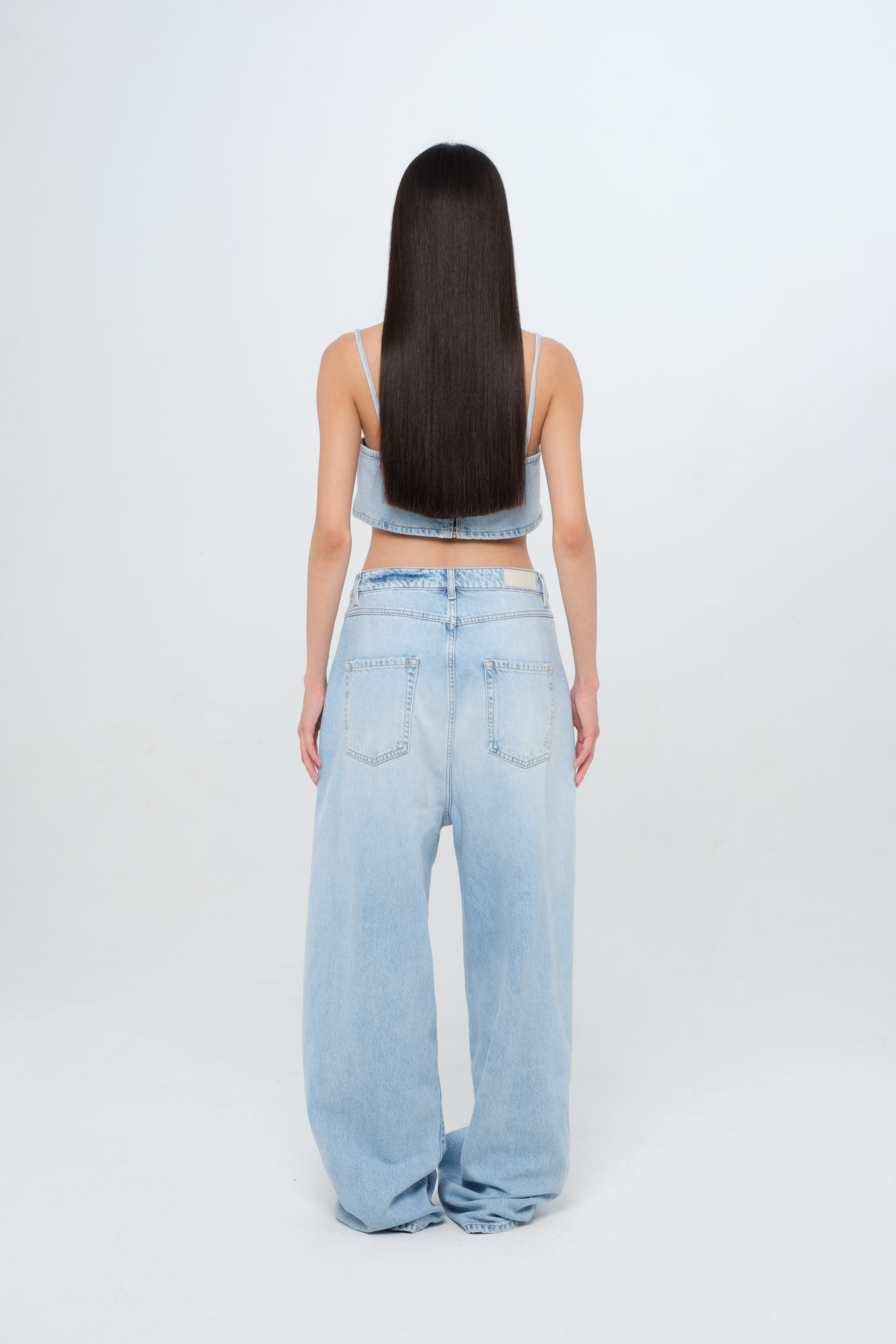 Back view of Coco women’s wide leg jeans in light wash, 100% rigid cotton denim, worn by a model with a denim top.