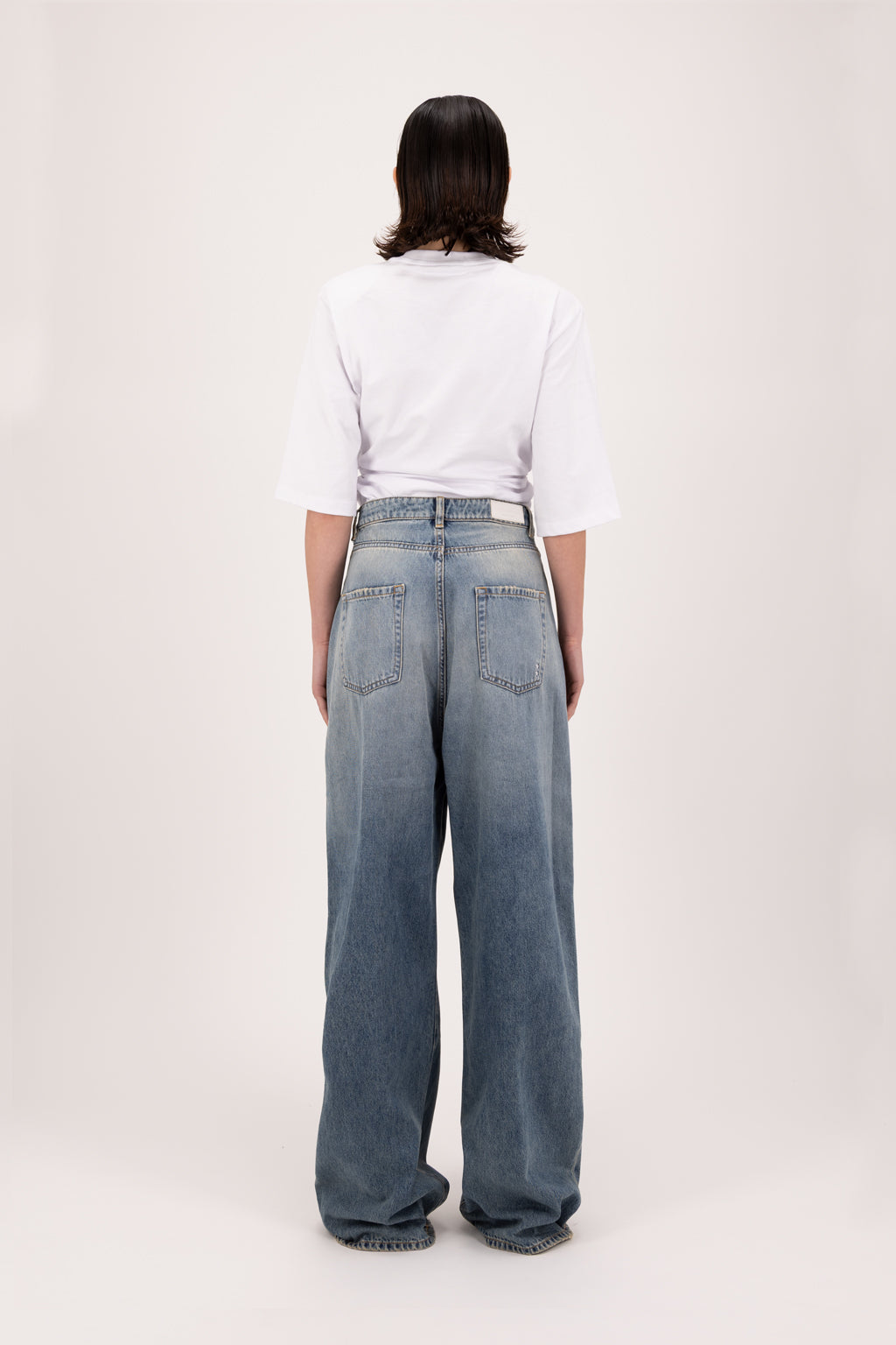 Back view of Coco women’s wide leg jeans in smoke blue wash, 100% rigid cotton denim, worn by a model with a white t-shirt.