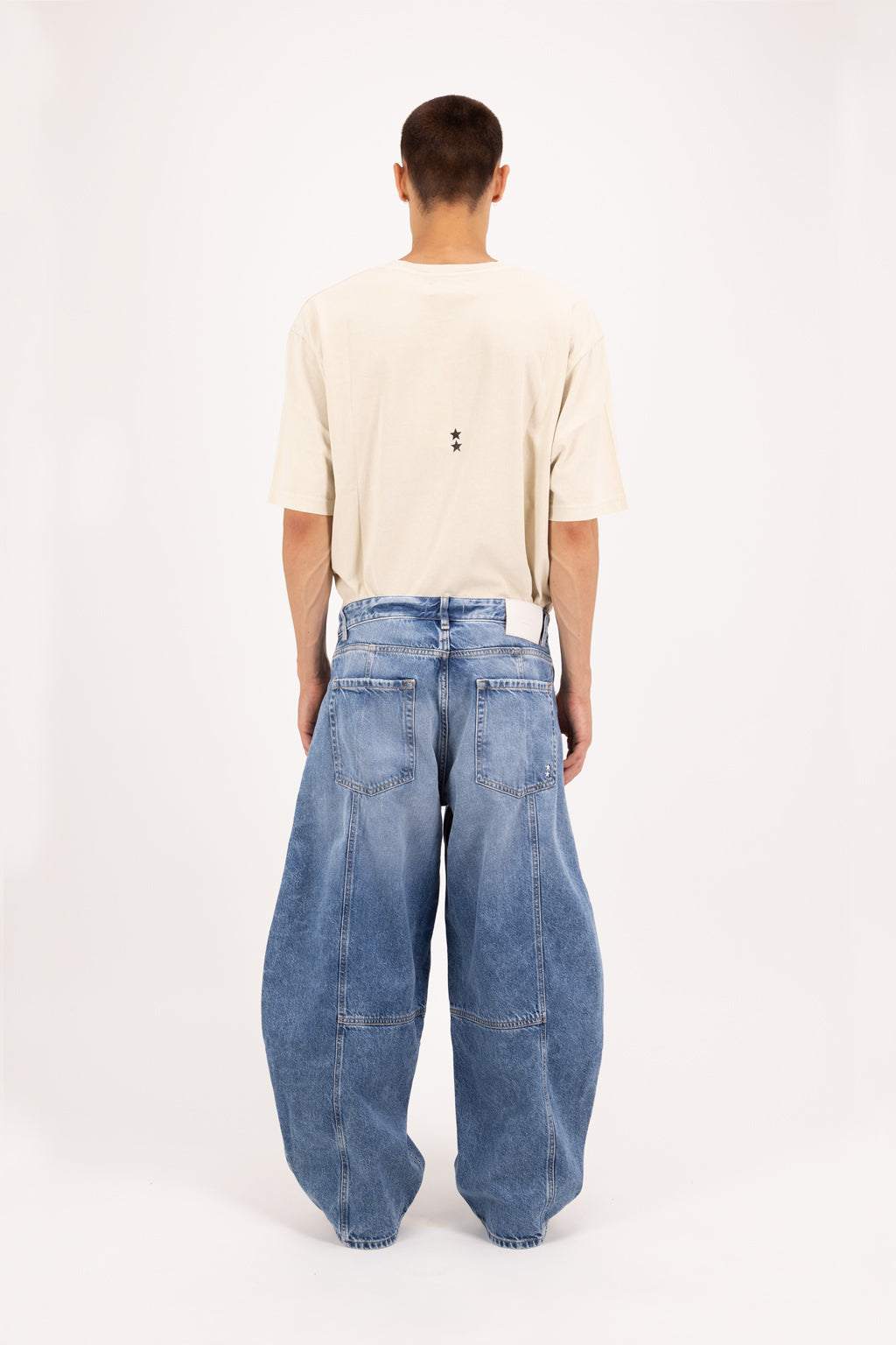 Back view of Cole men’s balloon jeans in eclipse wash, 100% rigid cotton denim, worn by a model with a desert t-shirt.