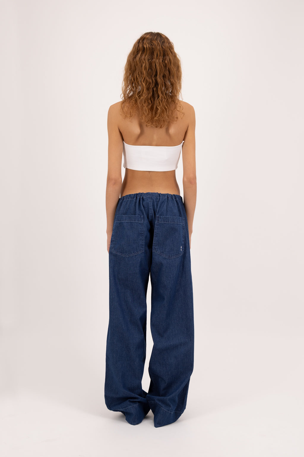 Back view of Cosy women’s wide leg jeans in night wash, 100% ultra light cotton denim, worn by a model with a white top.