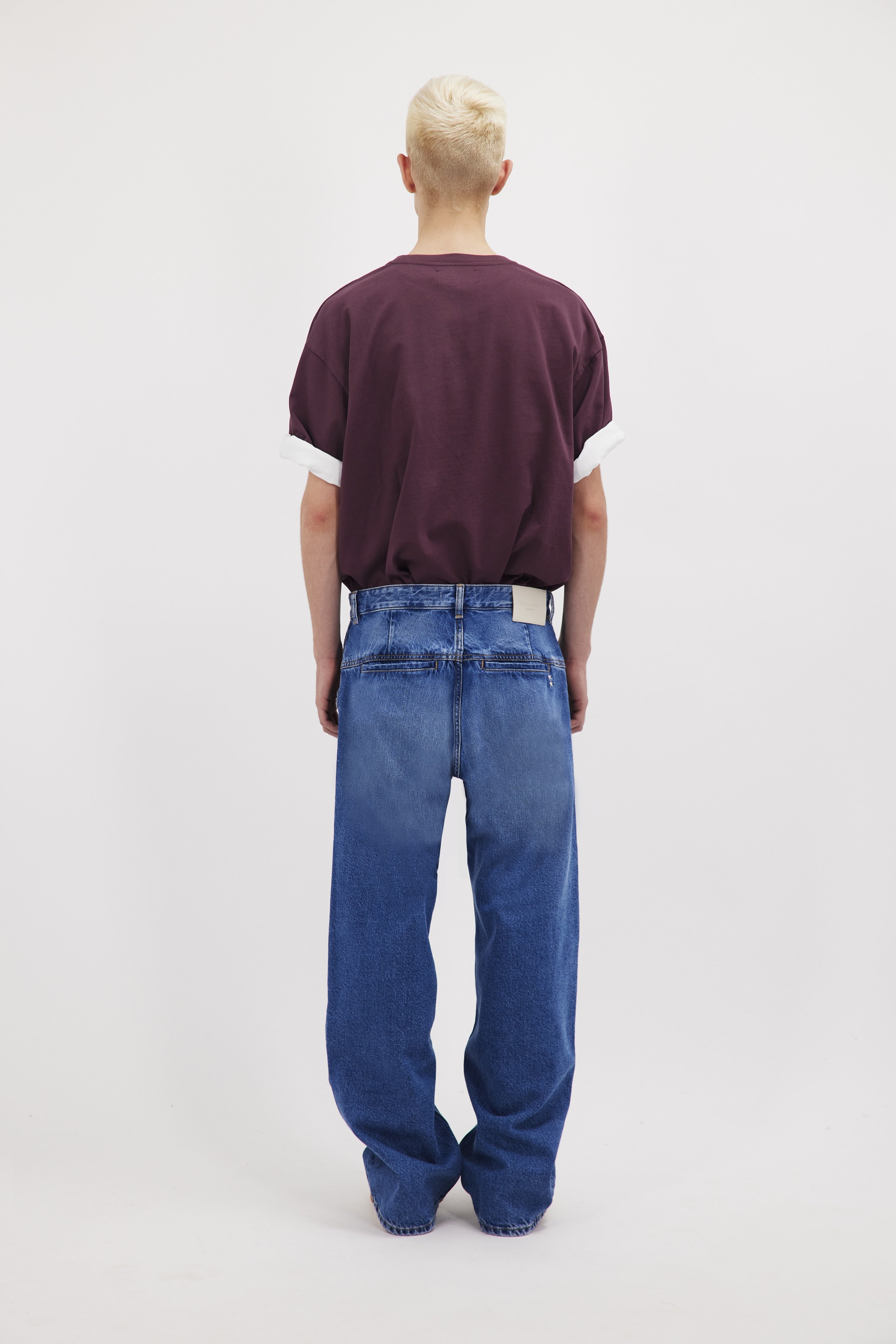 Back view of Dave men’s wide-cut leg jeans in eclipse wash, 100% rigid cotton denim, worn by a model with a cherry t-shirt.