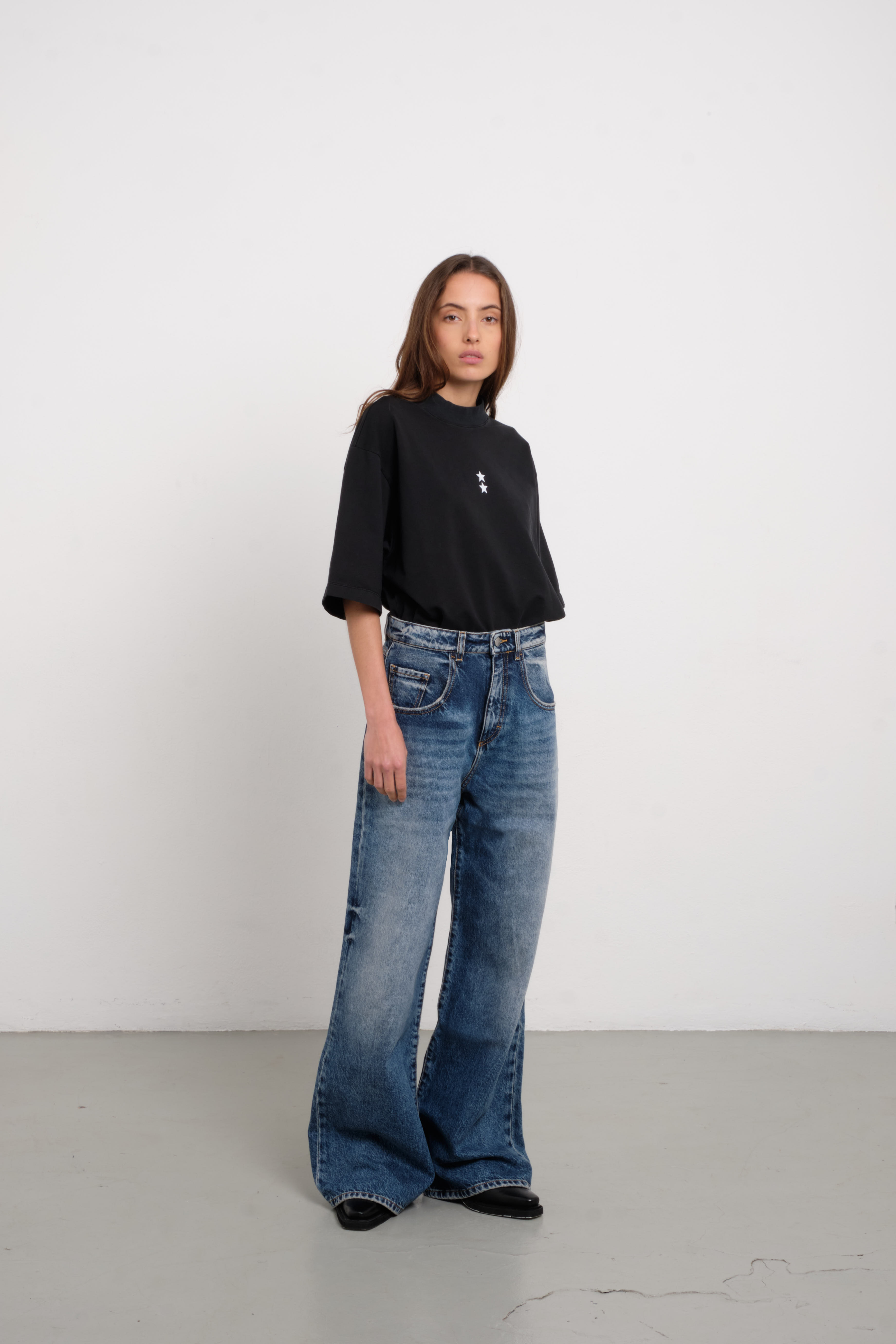 Debby women’s wide leg jeans in medium wash, 100% rigid cotton denim, worn by a model with a black shirt.
