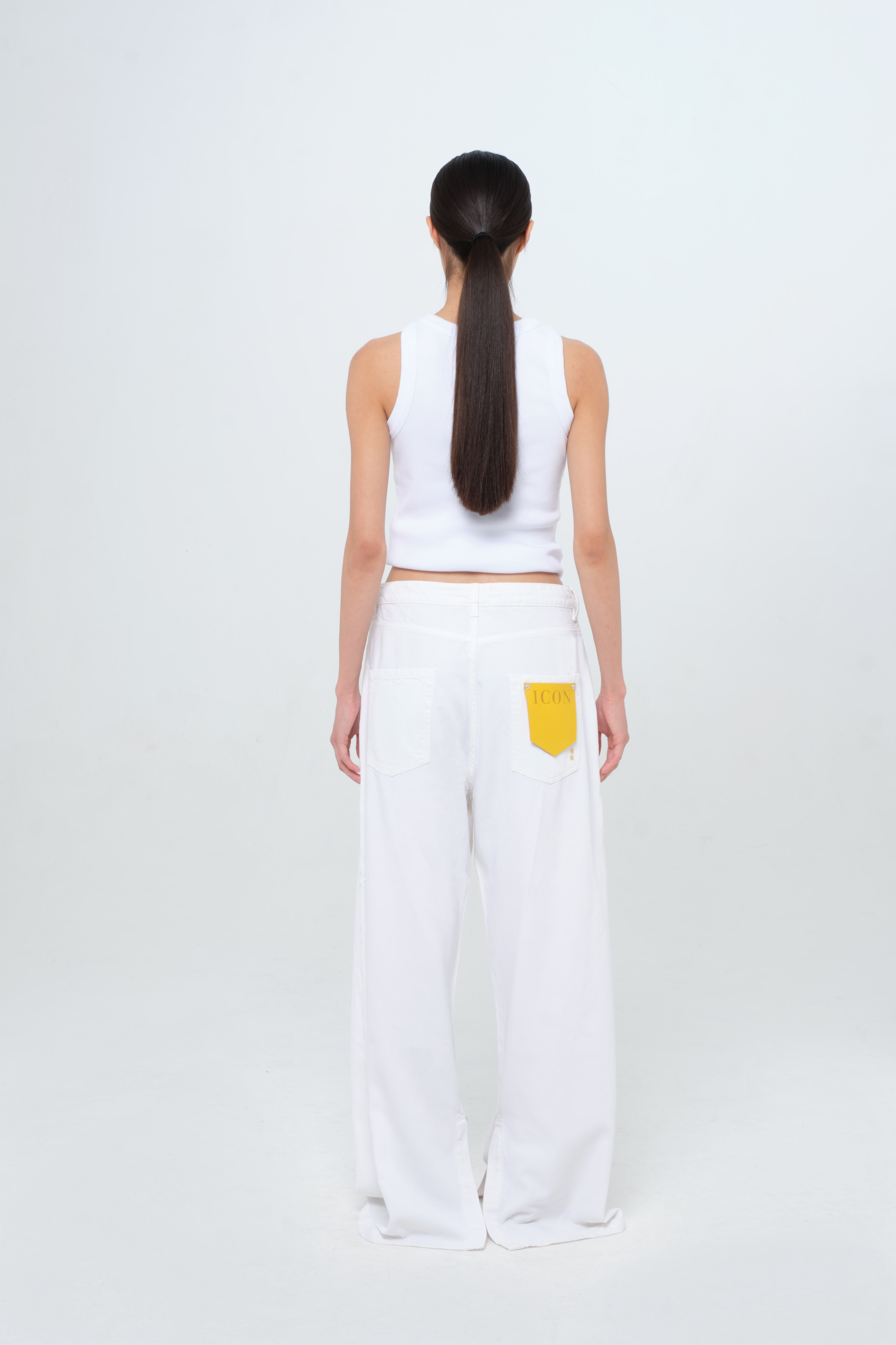 Back view of Gracy women’s wide leg jeans in white, 100% rigid soft cotton denim, worn by a model with a white tank top.
