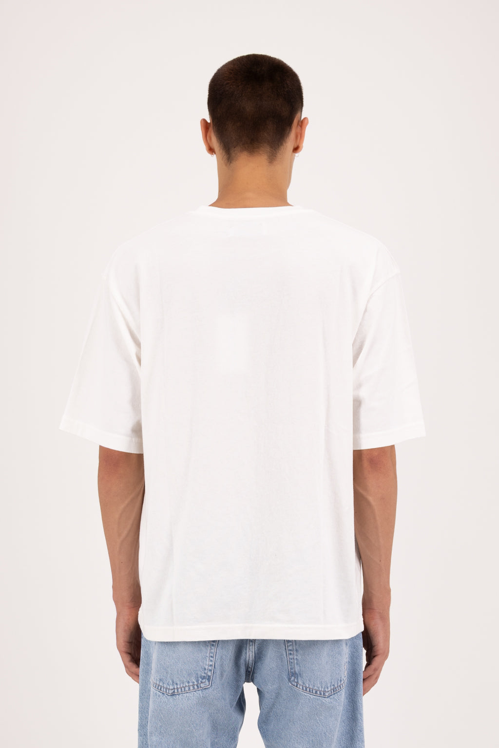 Back view of Haak men’s t-shirt in white, 100% cotton, worn by a model with jeans.
