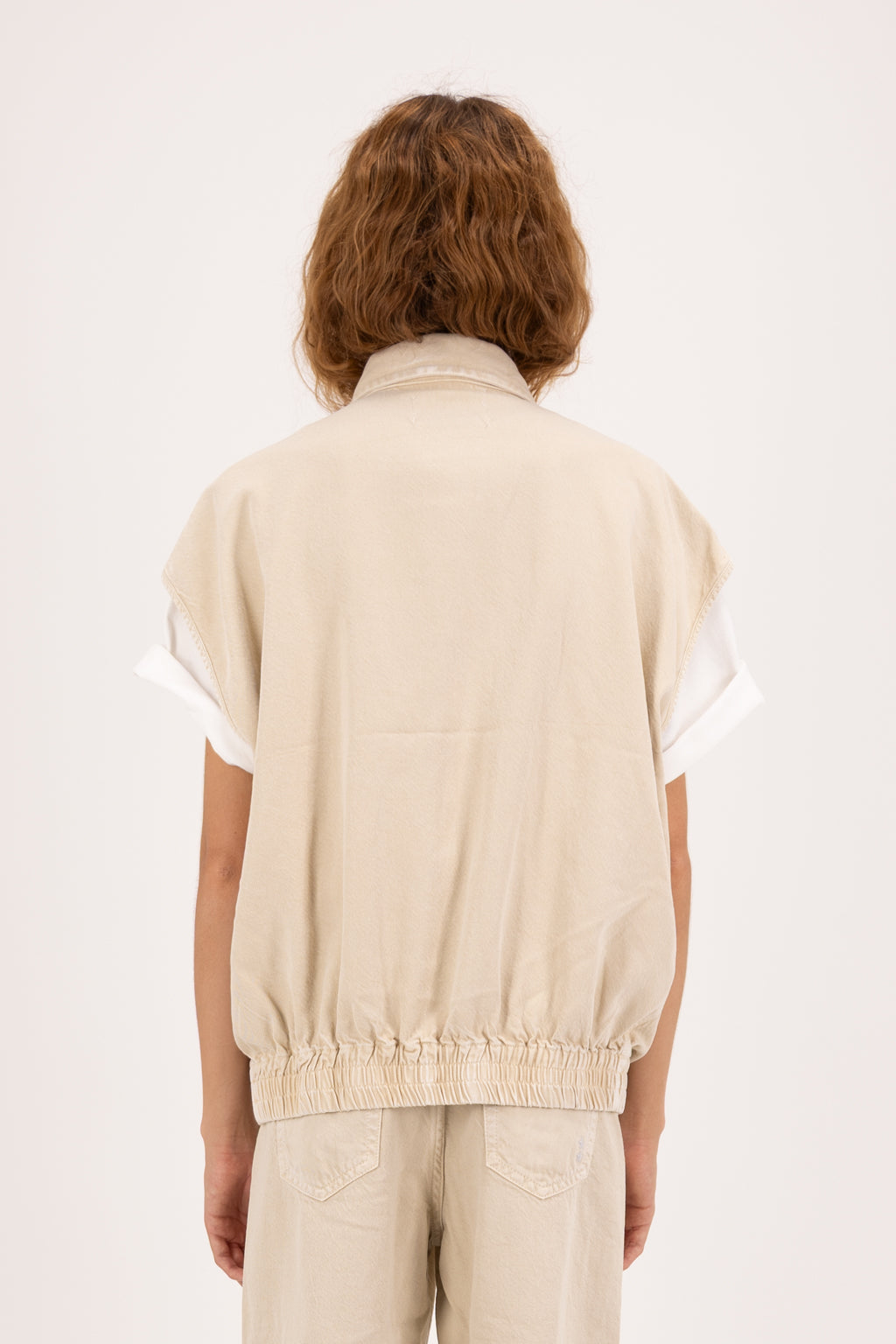 Back view of Ines women’s vest in desert wash, 100% rigid soft cotton denim, worn by a model with jeans.