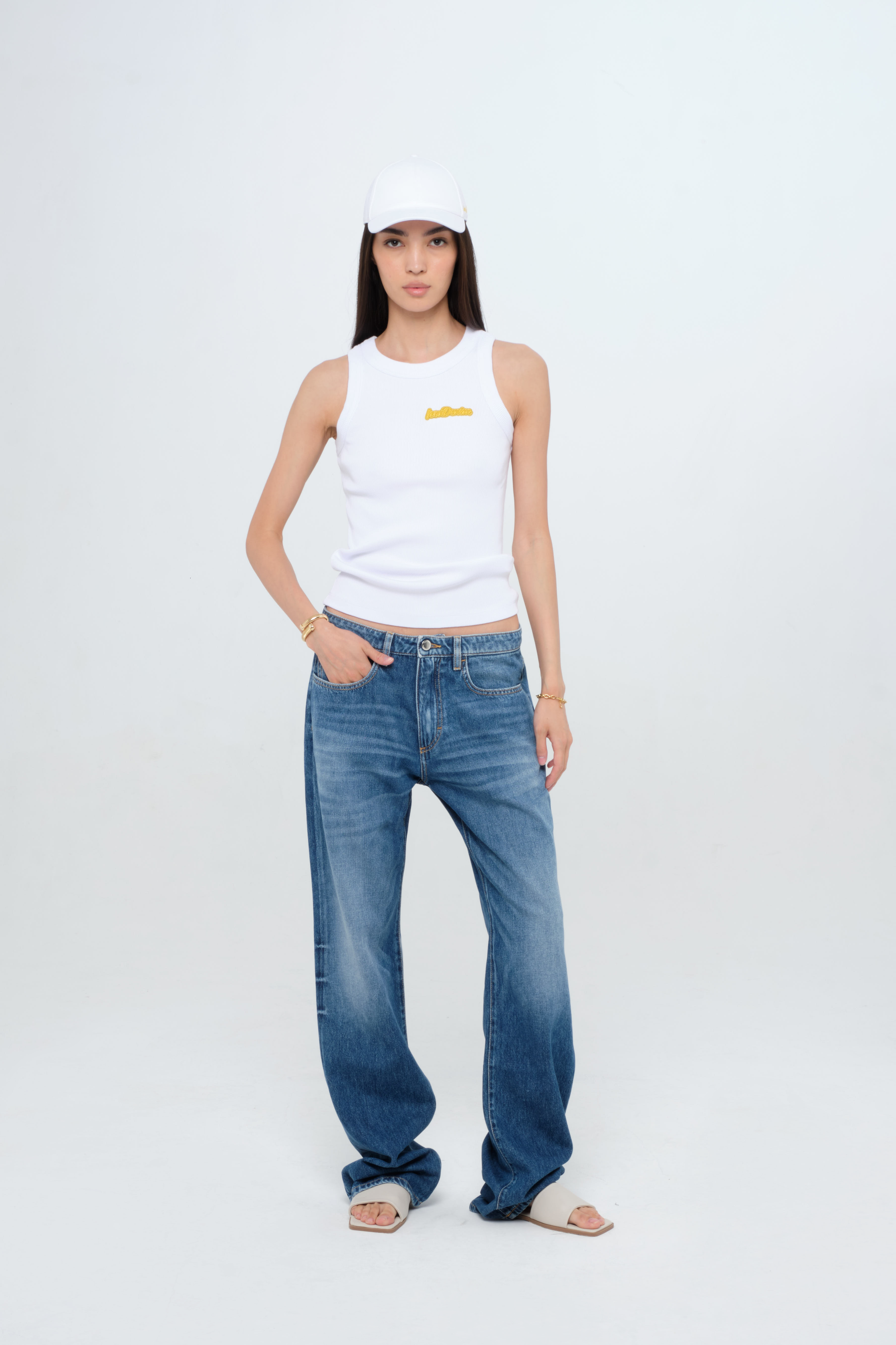 Iris women’s wide leg jeans in medium wash, 100% rigid cotton denim, worn by a model with a white tank top.
