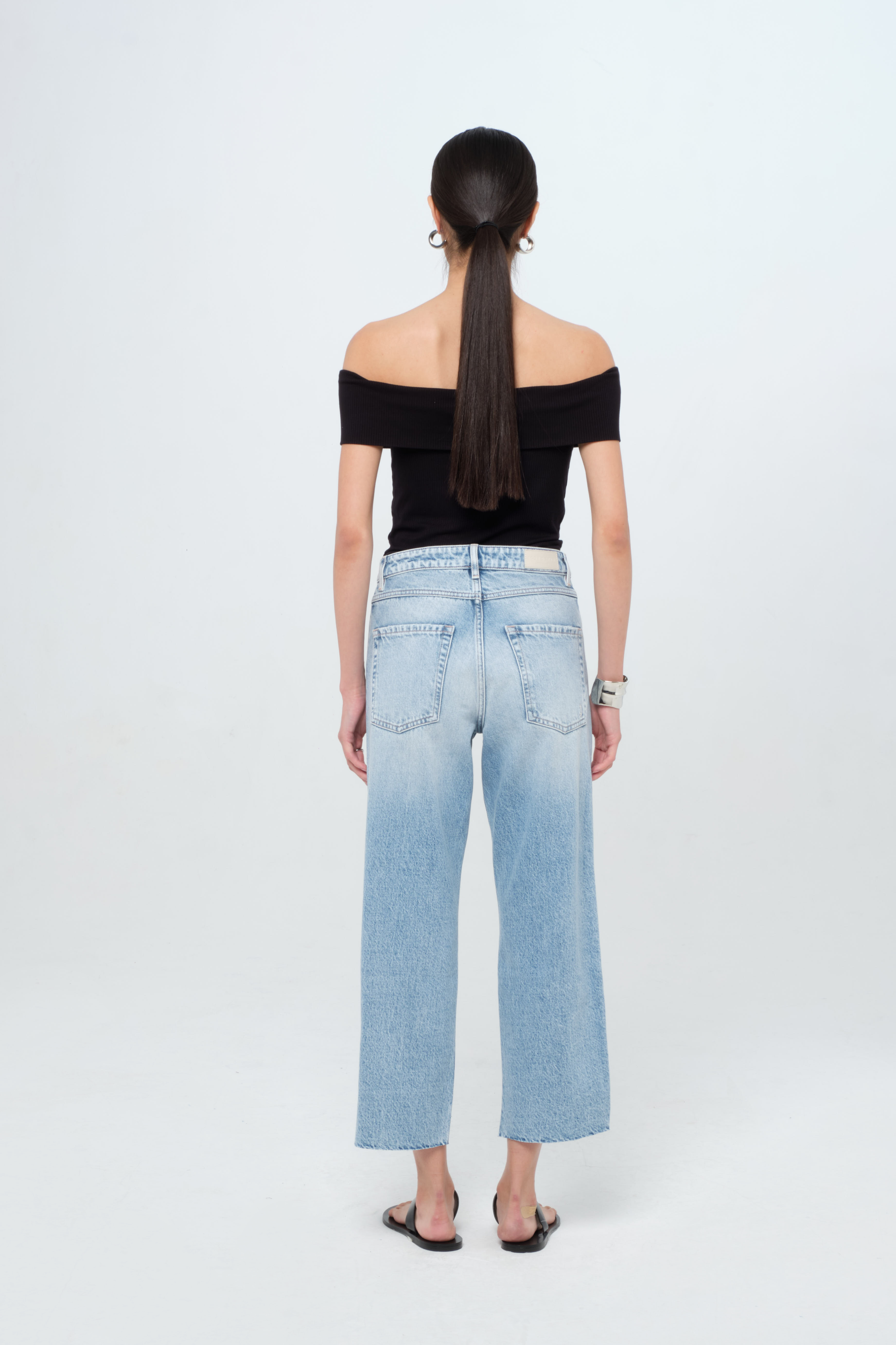 Back view of Jill women’s straight leg jeans in light wash, 100% rigid cotton denim, worn by a model with a black top.
