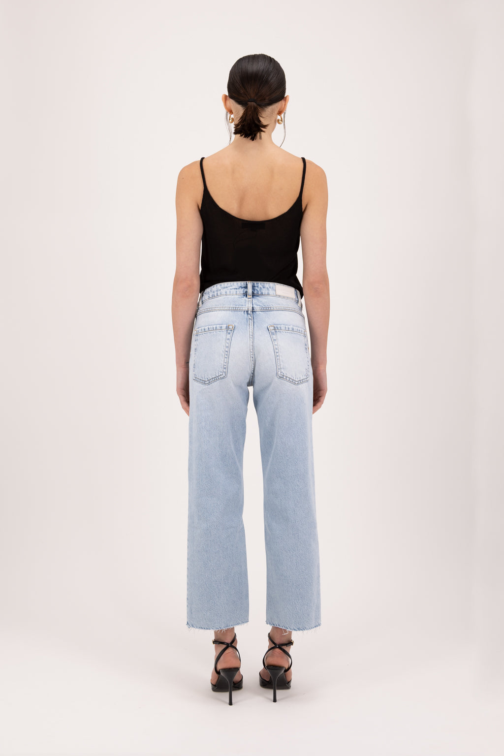 Back view of Jill women’s straight leg jeans in sky blue wash, 100% rigid cotton denim, worn by a model with a black top.