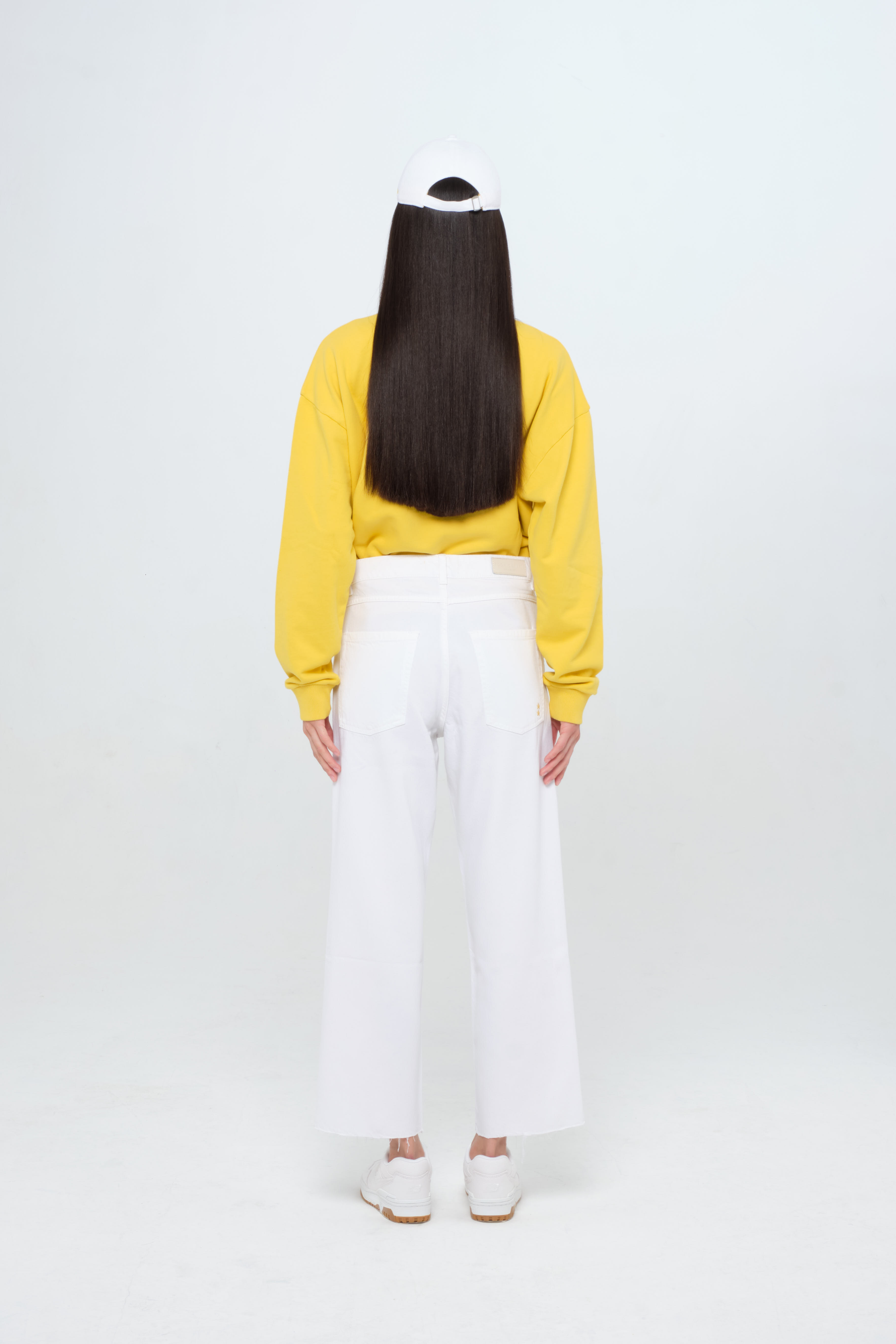 Back view of Jill women’s straight leg jeans in white, 100% rigid cotton denim, worn by a model with a yellow sweatshirt.