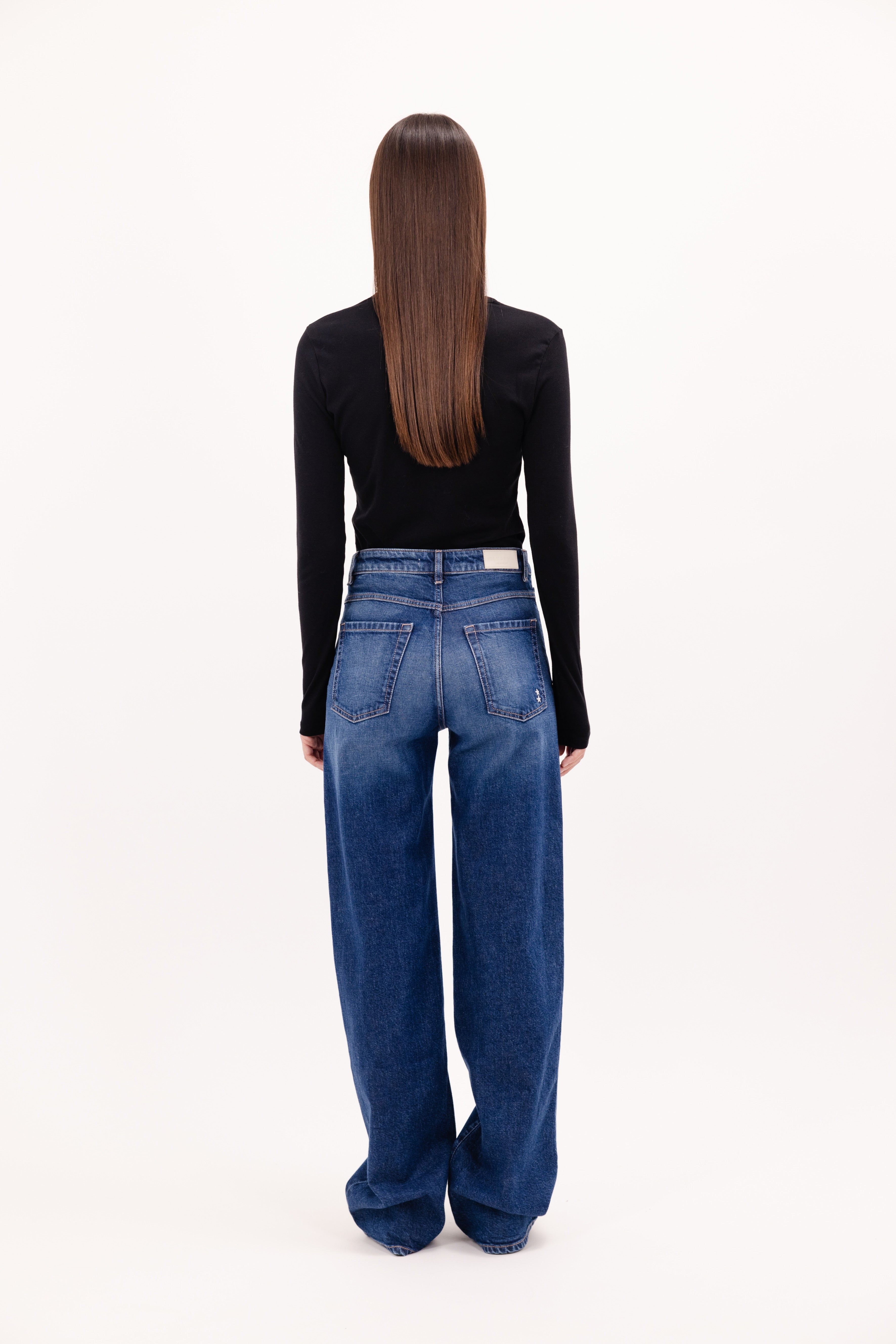 Back view of Joia women’s mom jeans in eclipse wash, 99% cotton denim and 1% Elastan fibers, worn by a model with a black longsleeve.