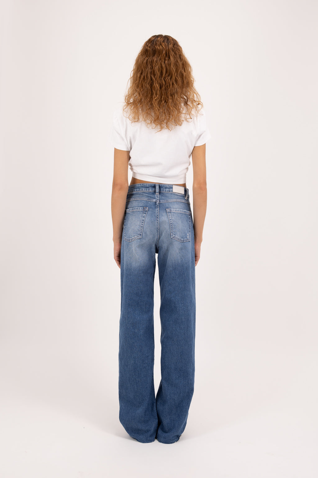Back view of Joia women’s mom jeans in eclipse wash, 99% cotton denim and 1% Elastan fibers, worn by a model with a white t-shirt.