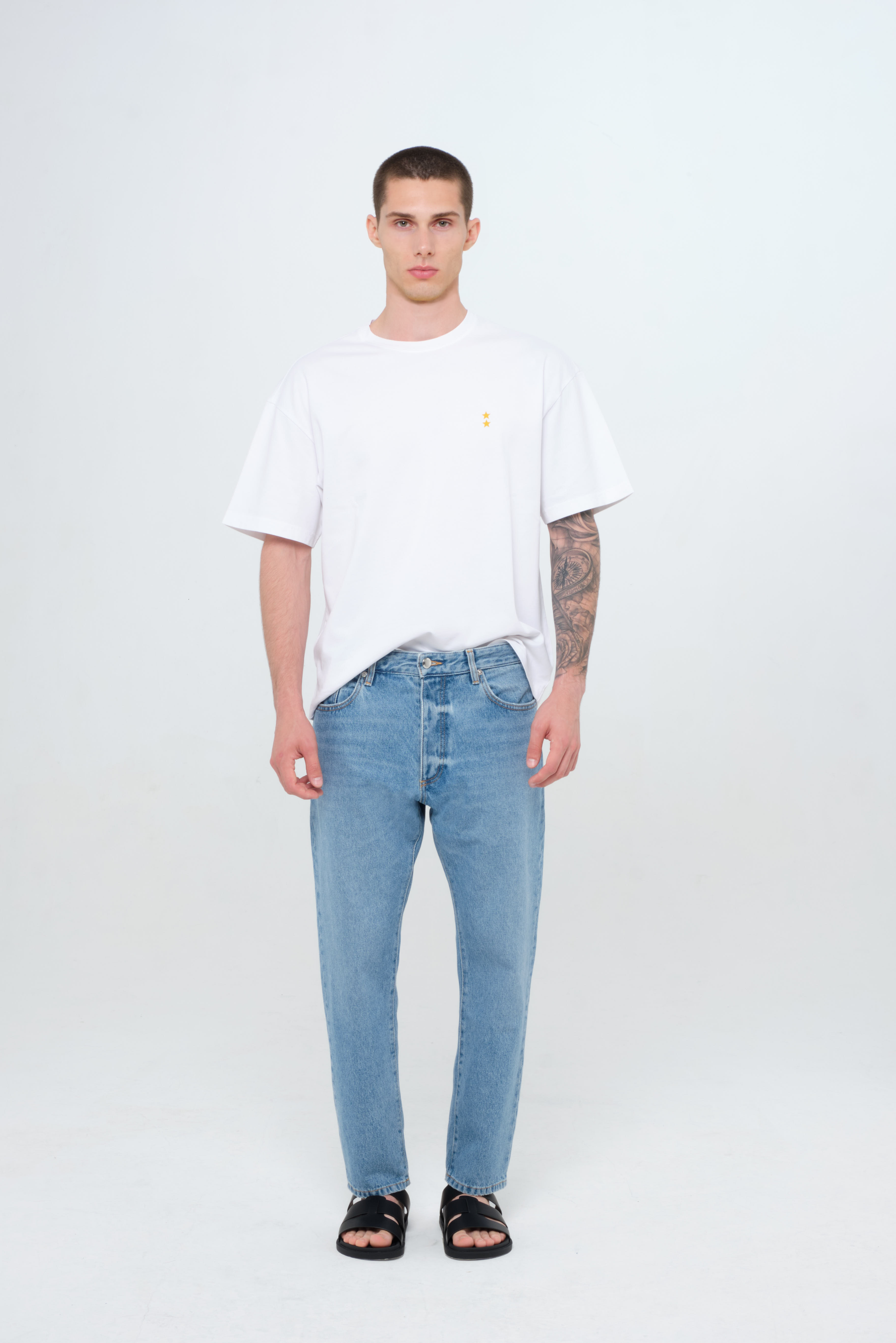 Josh Eco men’s carrot jeans in medium wash, 100% rigid organic cotton denim, worn by a model with a white t-shirt.
