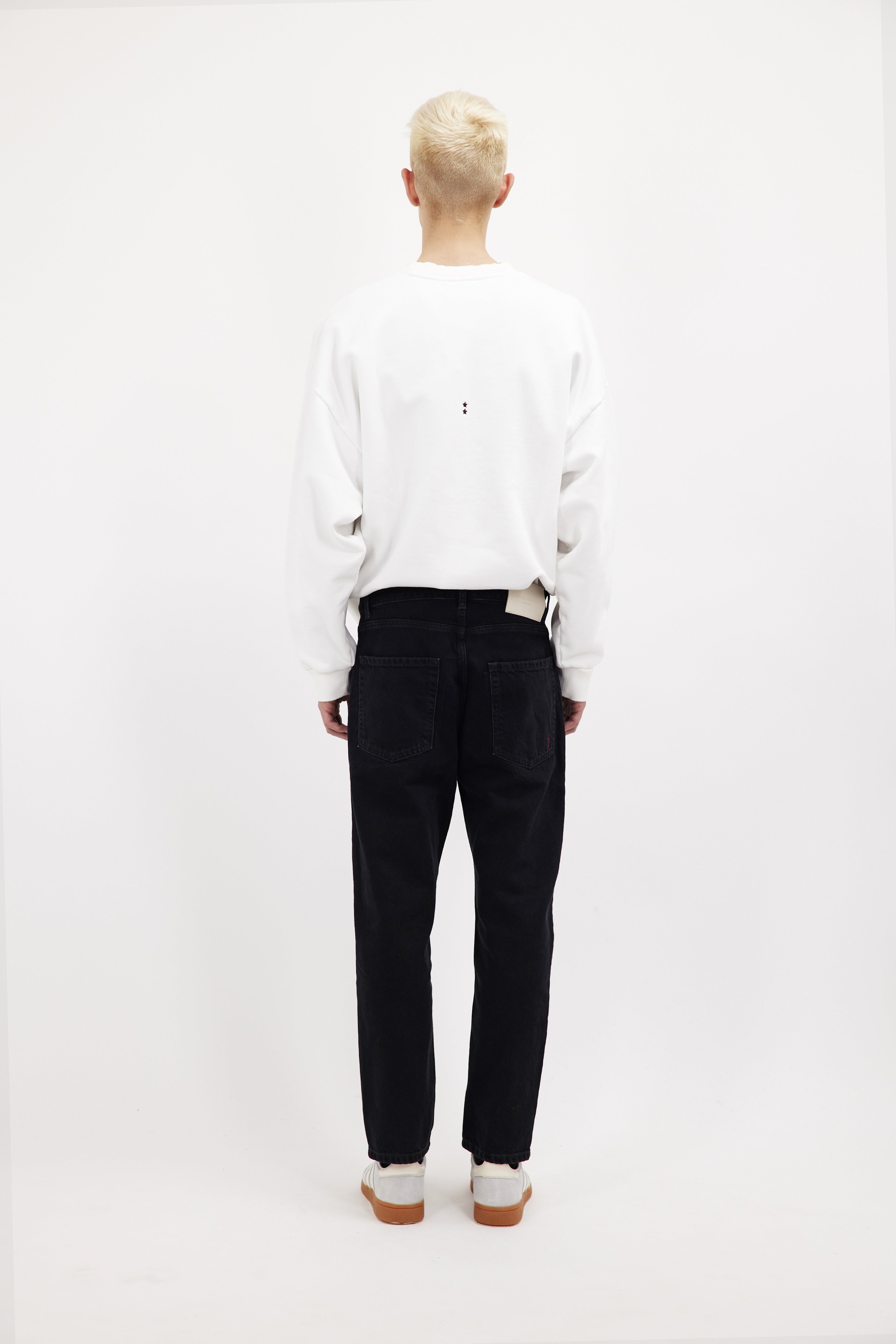 Back view of Josh men’s carrot jeans in graphite black wash, 100% rigid cotton denim, worn by a model with a white sweatshirt.