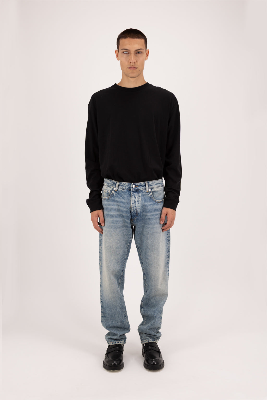 Kanye men’s baggy jeans in smoke blue wash, 100% rigid cotton denim, worn by a model with a black sweatshirt.