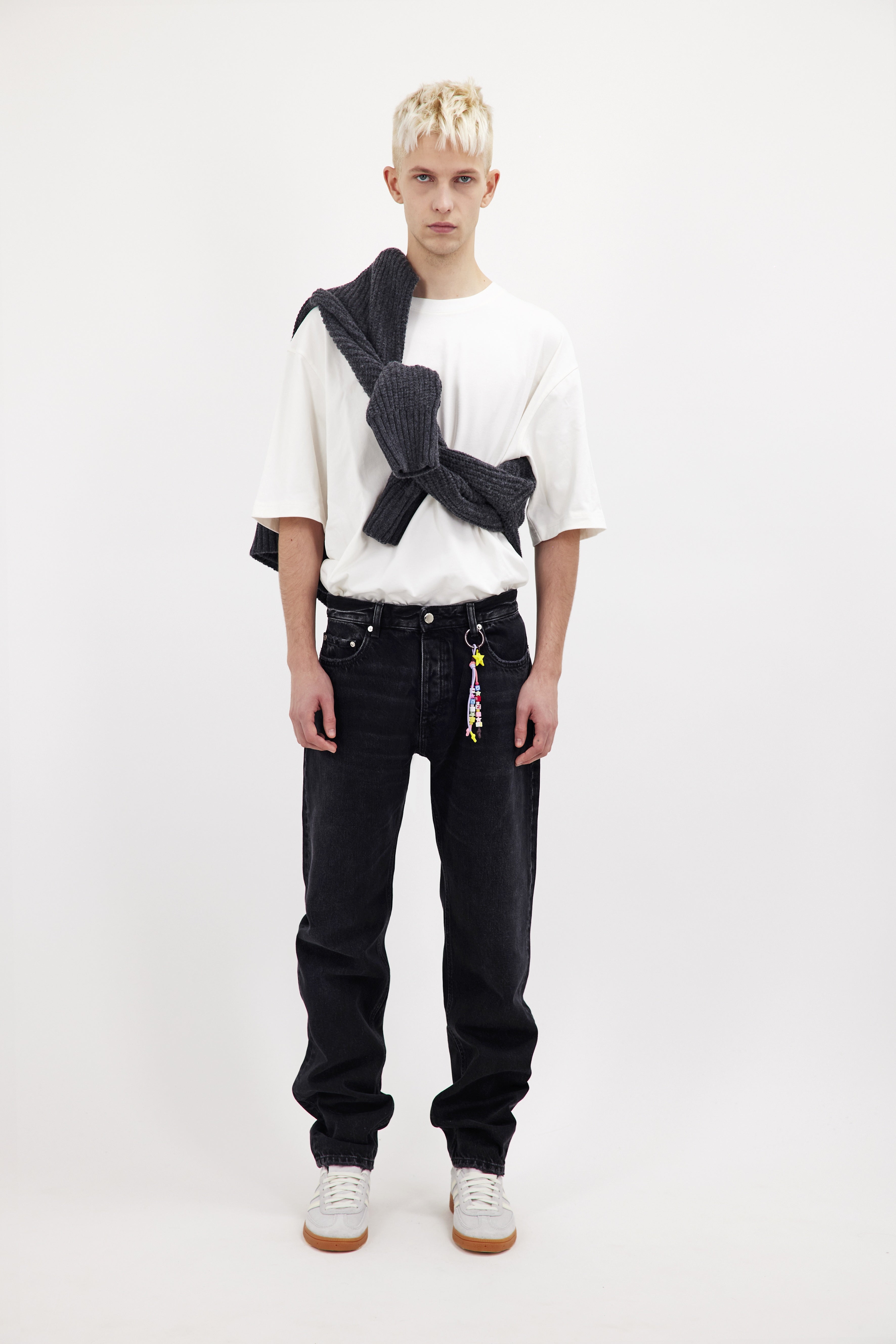 Kanye men’s loose jeans in graphite black wash, 100% rigid cotton denim, worn by a model with a white t-shirt.